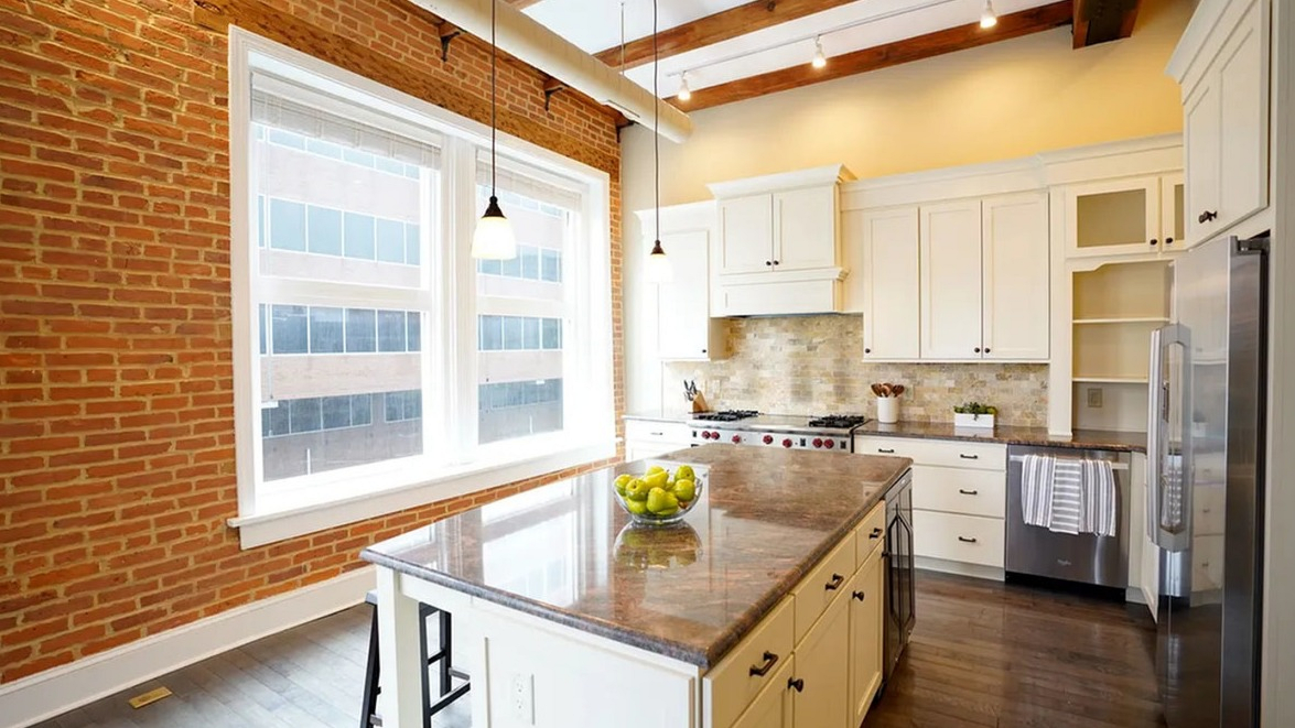 Chic modern kitchen with brick accent wall, large island, and stainless steel appliances showcasing warm, inviting ambiance.