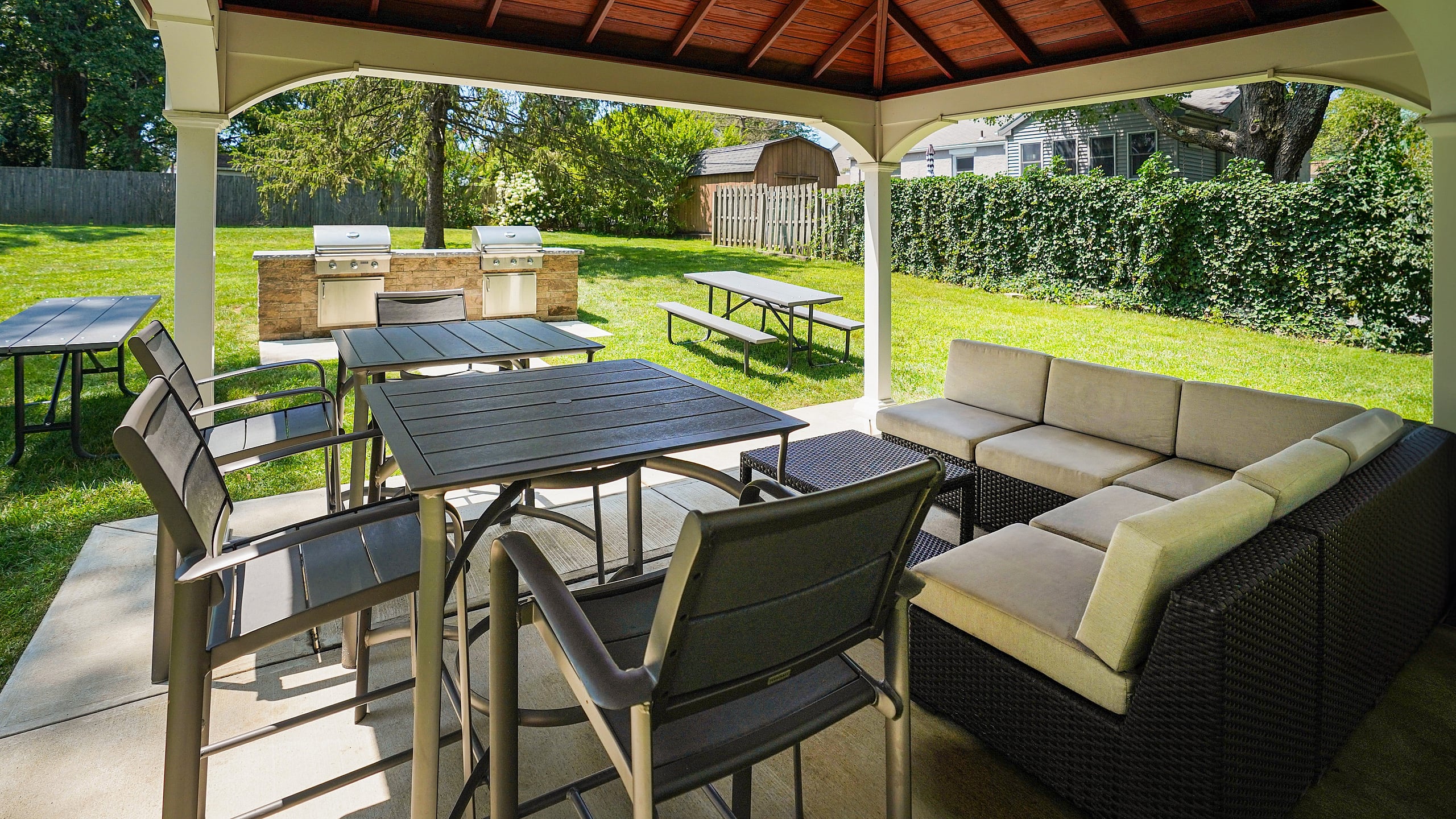 Charming outdoor patio featuring a cozy seating area under a stylish gazebo, perfect for entertaining with built-in grills and picnic tables.