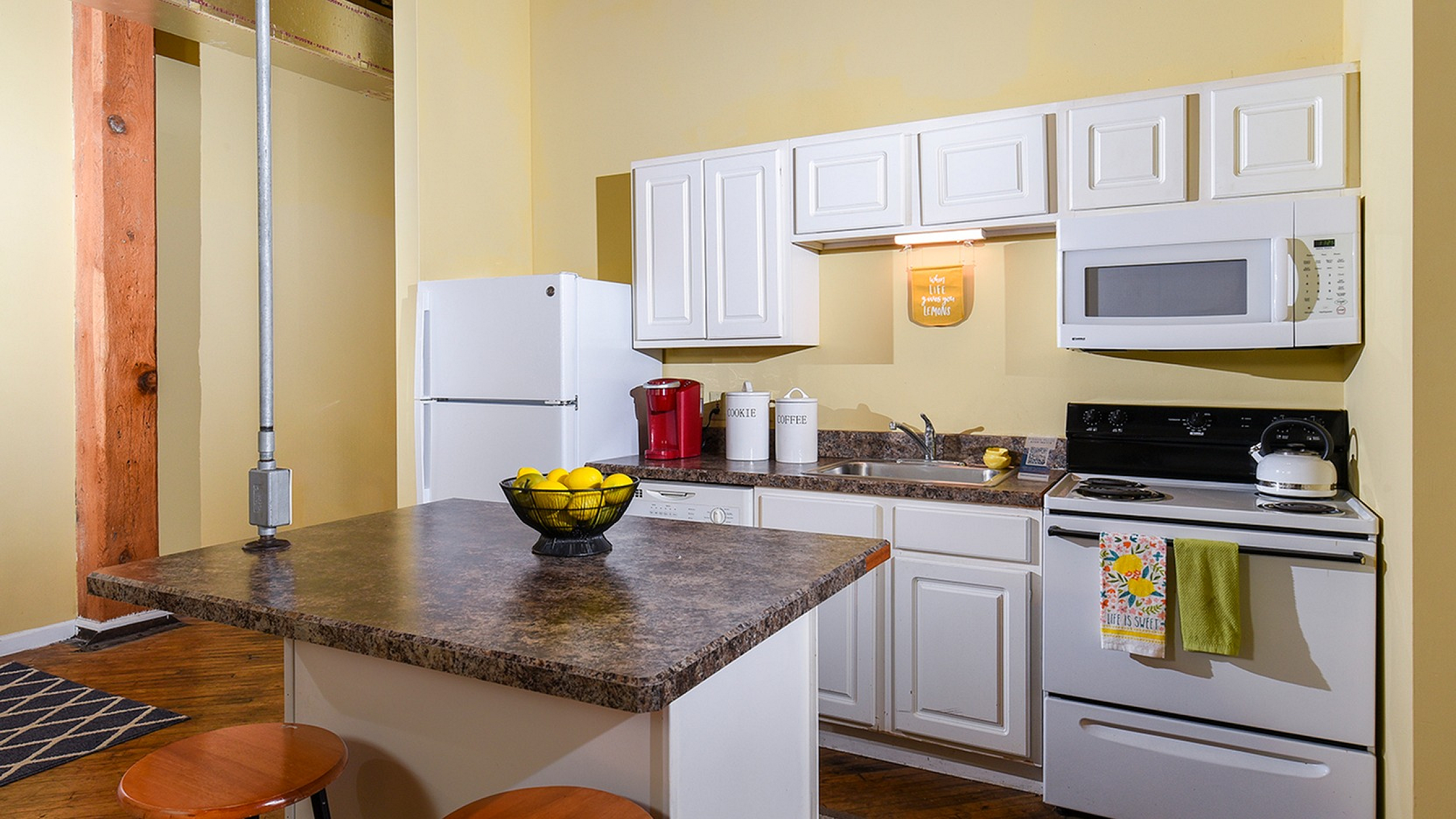 Charming kitchen with modern white cabinetry, sleek countertops, and a cozy island with bar stools, perfect for casual dining.