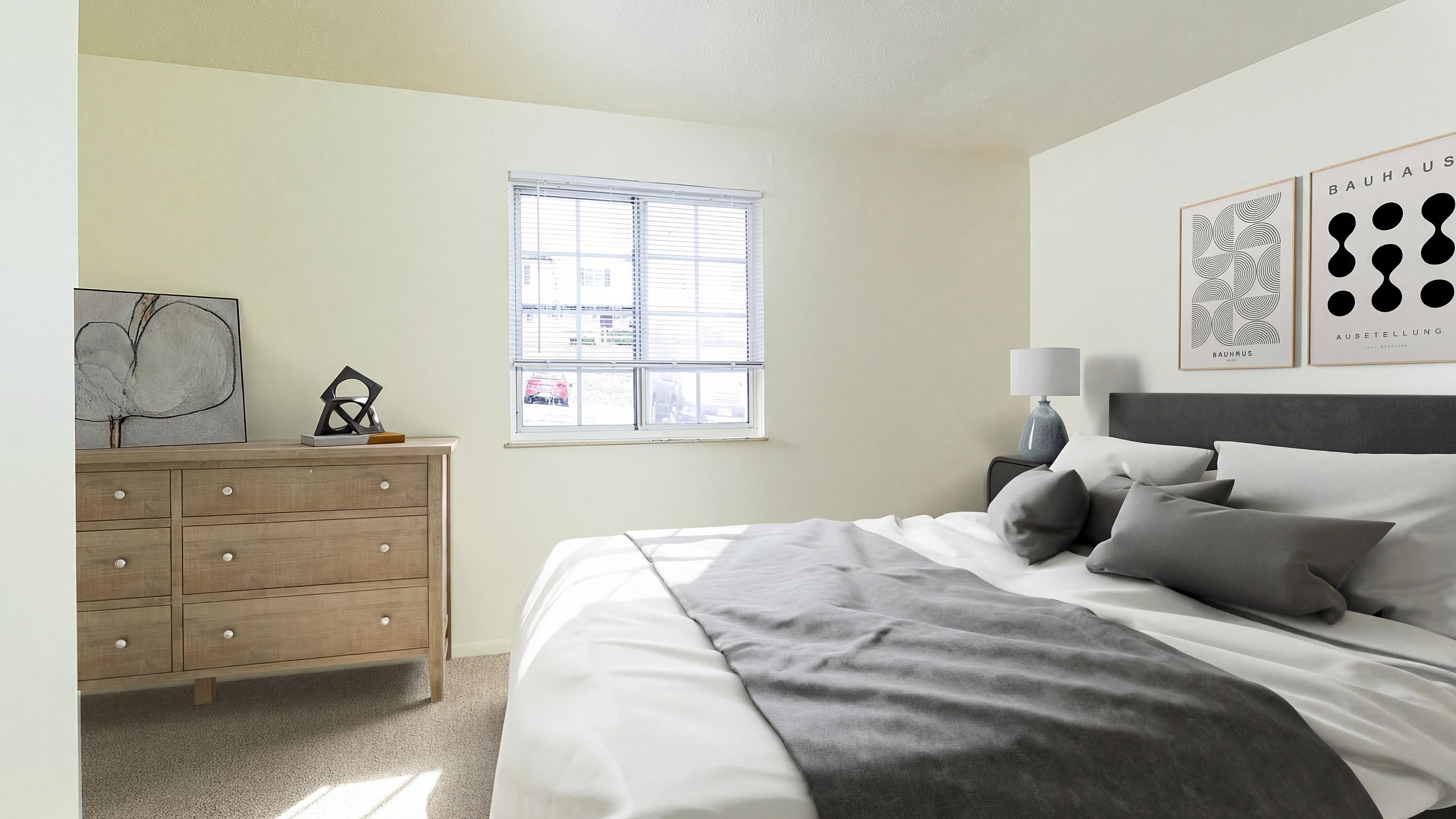 Bright and inviting bedroom with a plush bed, modern decor, and ample natural light through a large window, perfect for serene living.