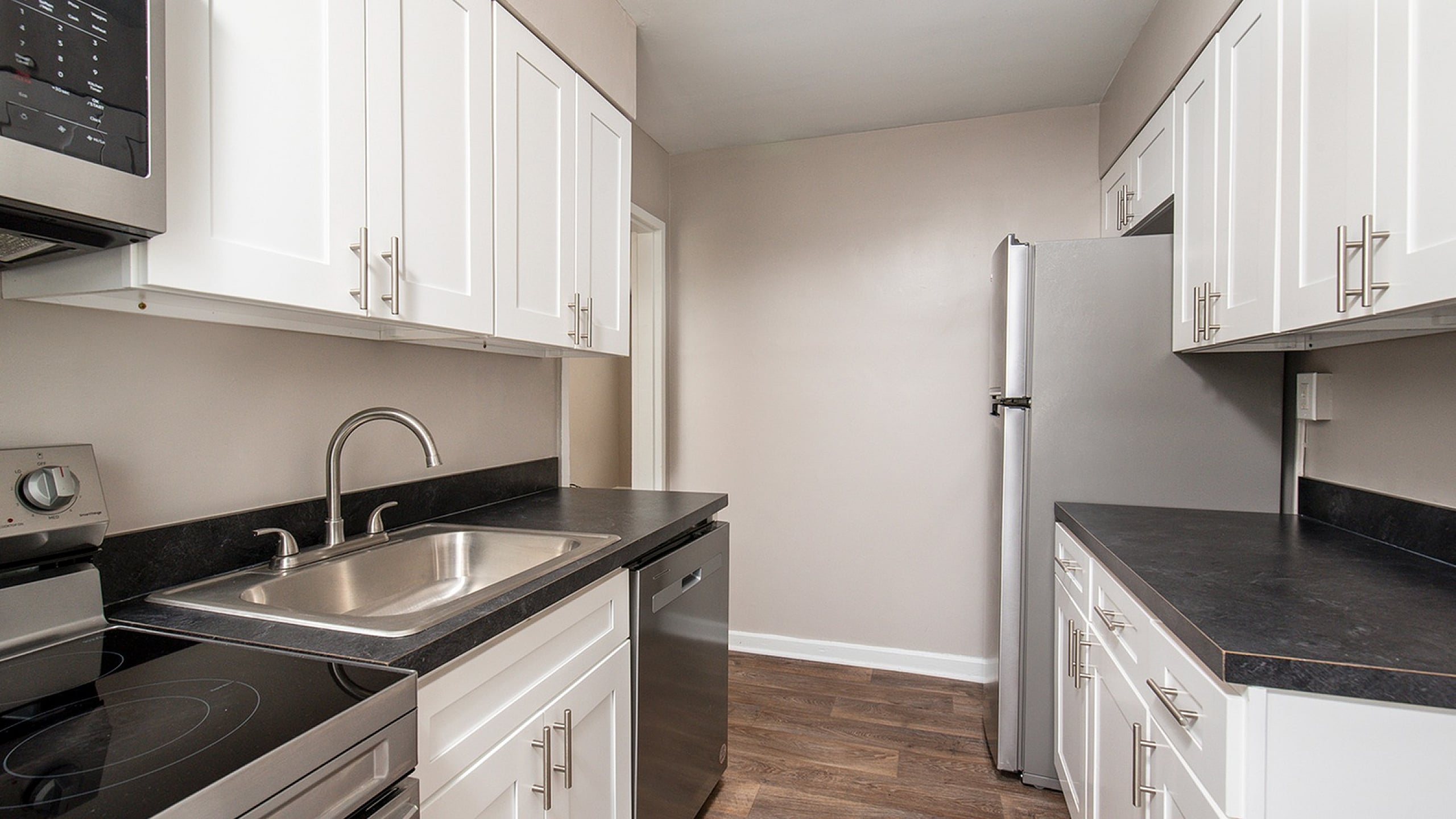 Modern kitchen with sleek stainless steel appliances, white cabinetry, and elegant dark countertops.