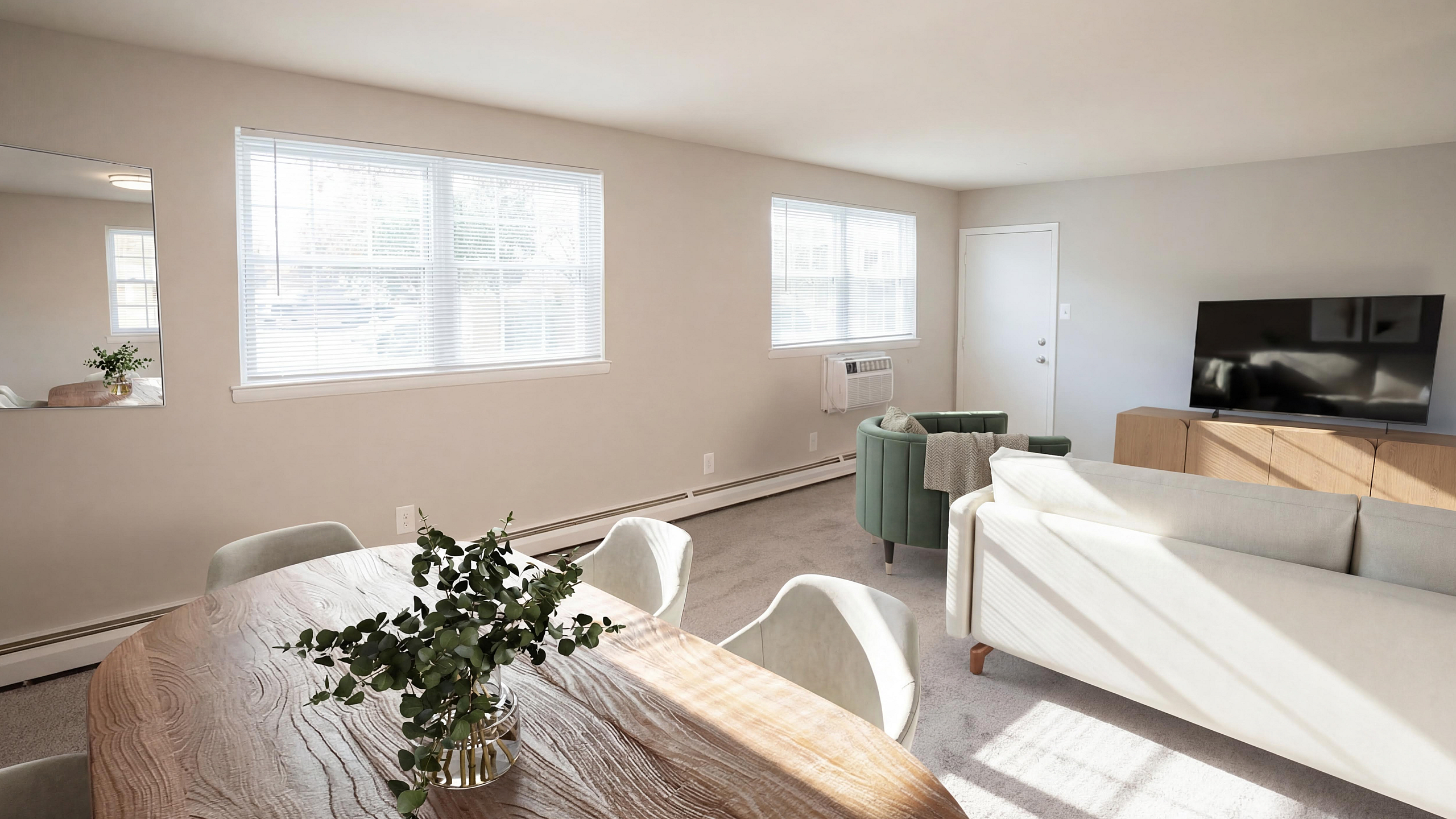 Bright and spacious living room with modern furniture, natural light, and a cozy dining area.