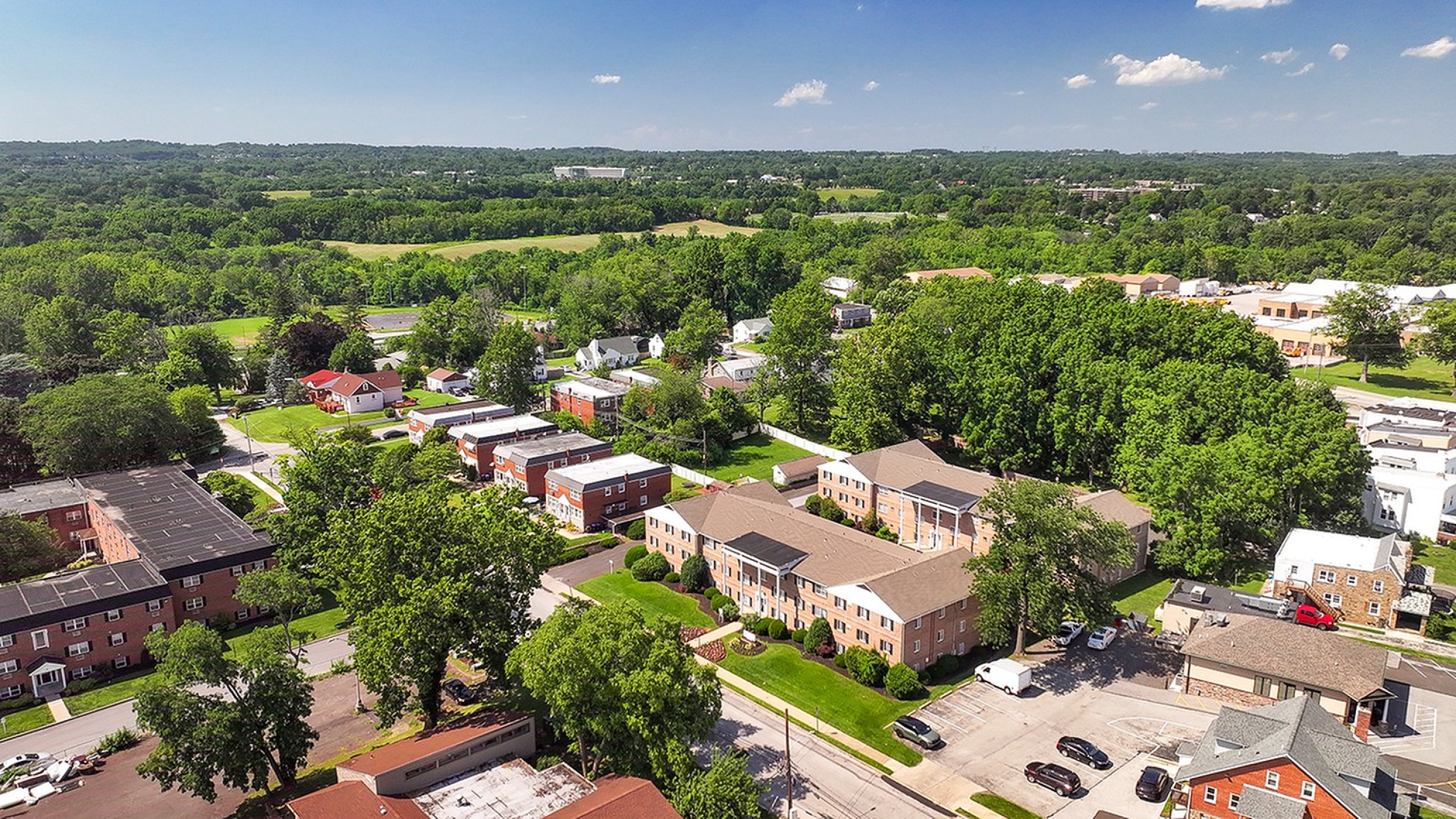 Scenic aerial view of a charming suburban neighborhood with lush green landscapes and well-maintained apartment buildings, perfect for a peaceful lifestyle.
