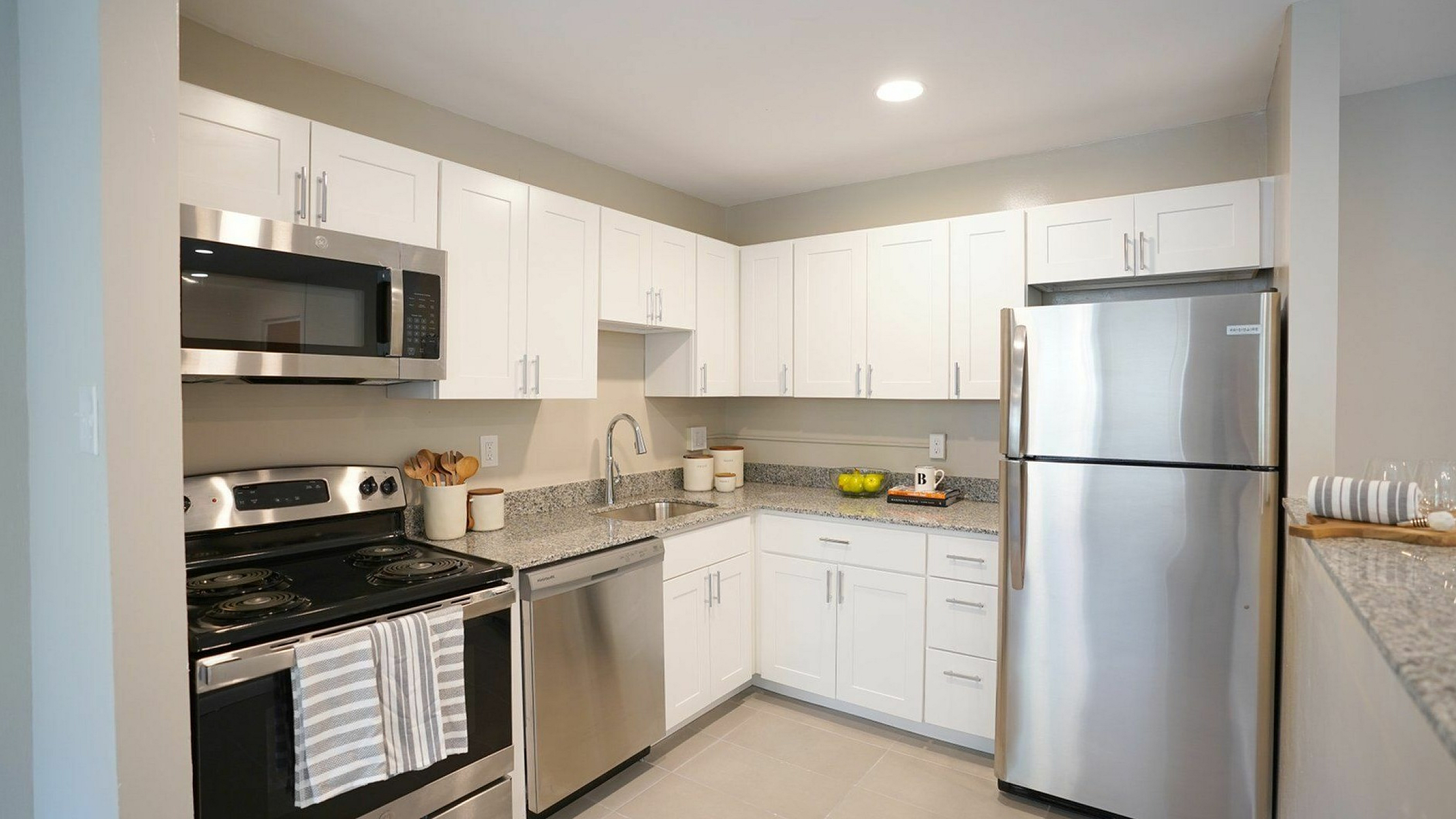 Modern kitchen with stainless steel appliances, sleek white cabinets, and elegant granite countertops, designed for style and functionality.