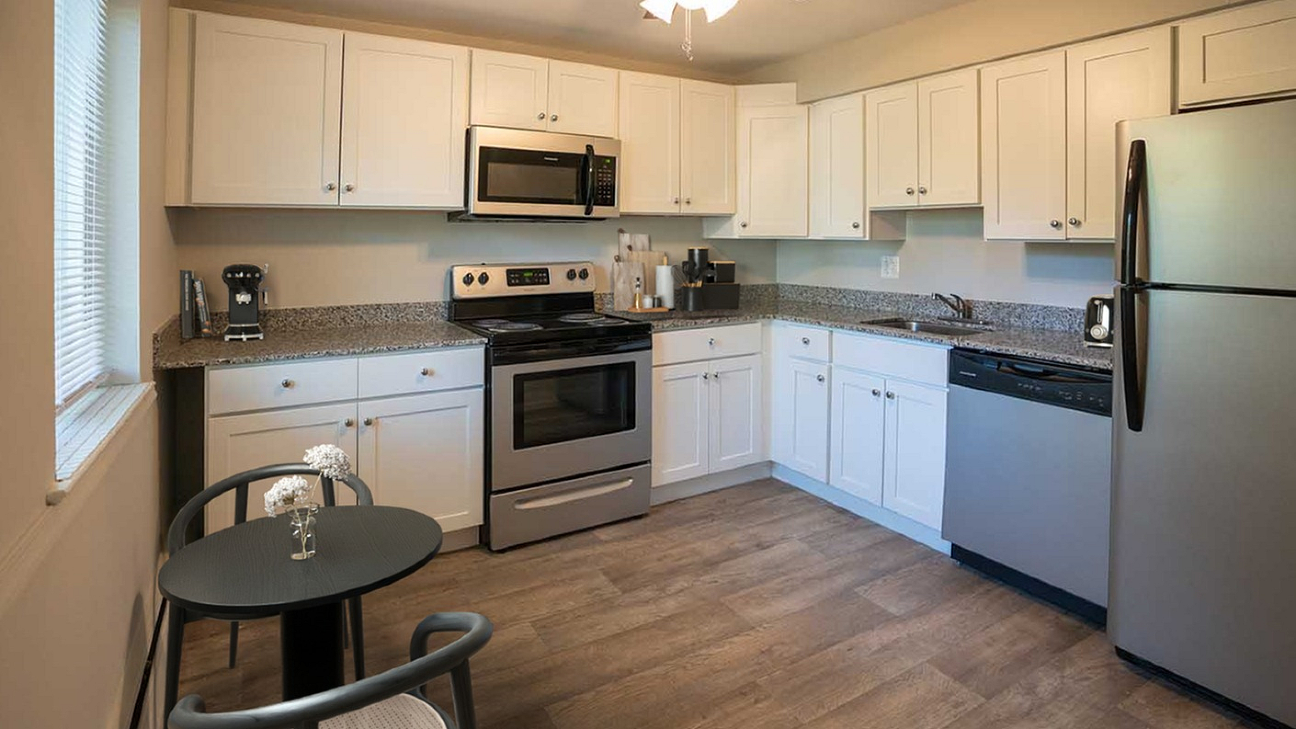Modern kitchen with sleek stainless steel appliances, elegant white cabinetry, and a cozy dining nook with natural light.