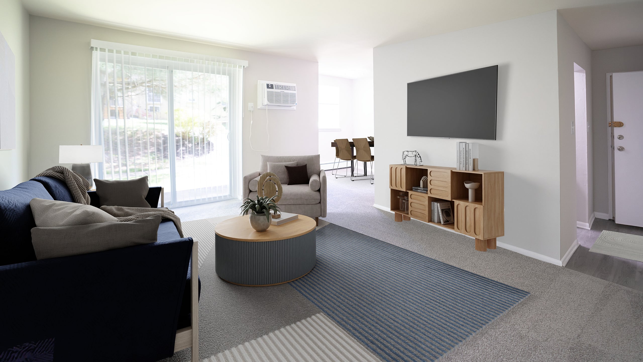 Bright, contemporary living room with plush blue sofa, modern decor, and sleek TV setup, enhanced by natural light from sliding glass doors leading to an inviting outdoor space.