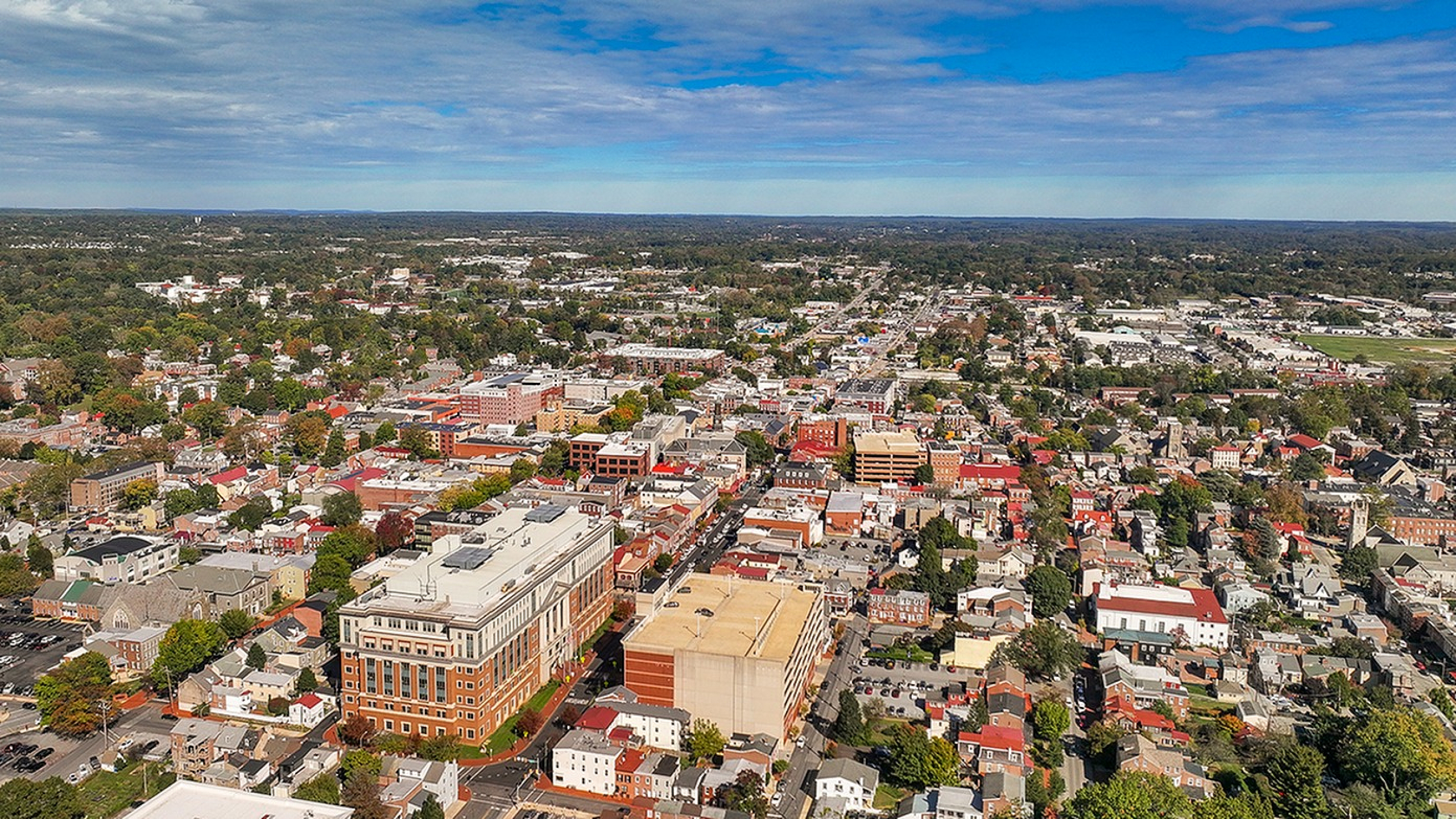 Breathtaking aerial view of a vibrant urban area with a harmonious blend of greenery and architecture under a clear blue sky.