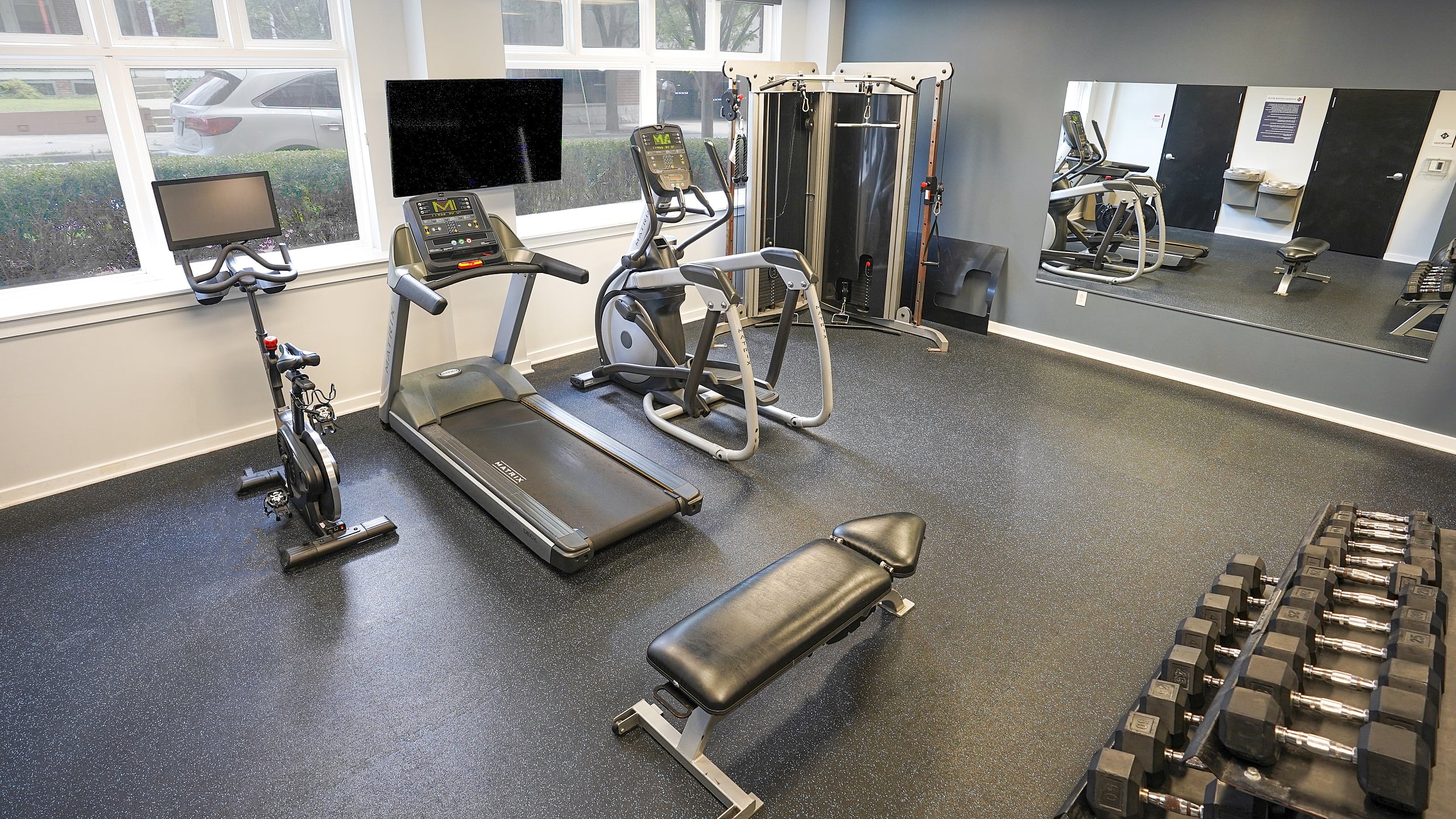 Modern fitness center featuring state-of-the-art equipment, including treadmills, stationary bikes, and a dumbbell rack set for an energizing workout experience.