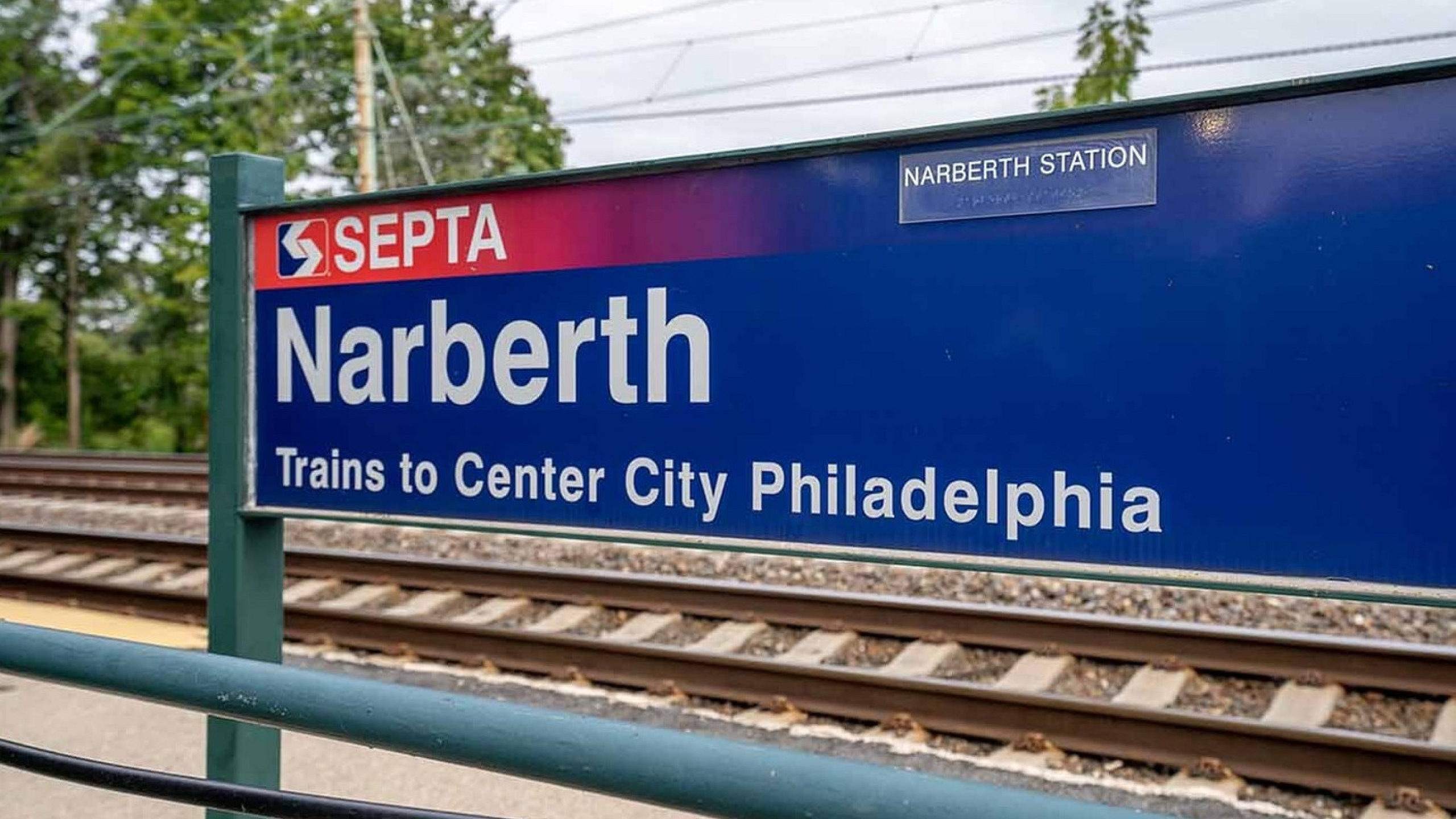 Vibrant Narberth Station sign with tracks, offering convenient access to Center City Philadelphia.