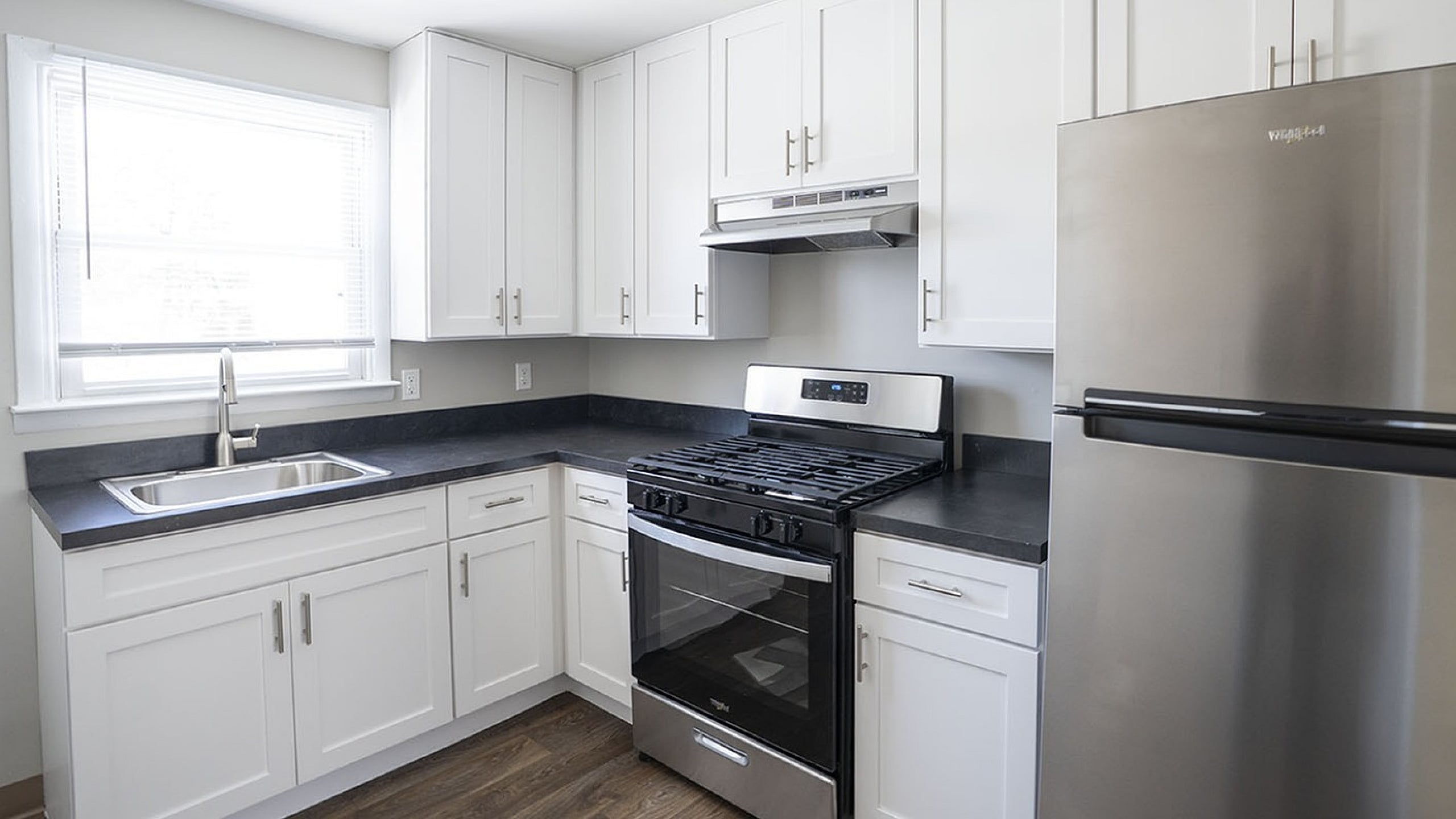 Modern kitchen with sleek stainless steel appliances, white cabinetry, and elegant dark countertops.
