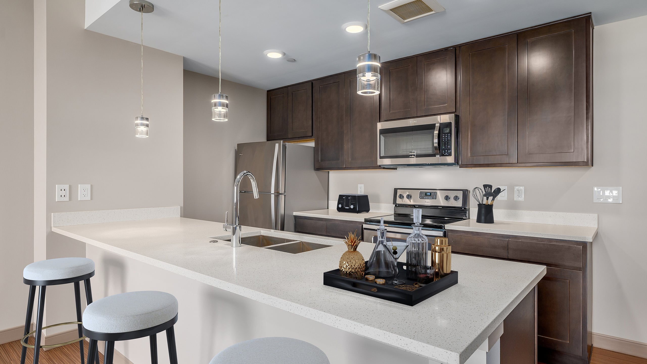 Modern kitchen with sleek stainless steel appliances, elegant dark wood cabinets, and a spacious white quartz countertop island with stylish pendant lighting.