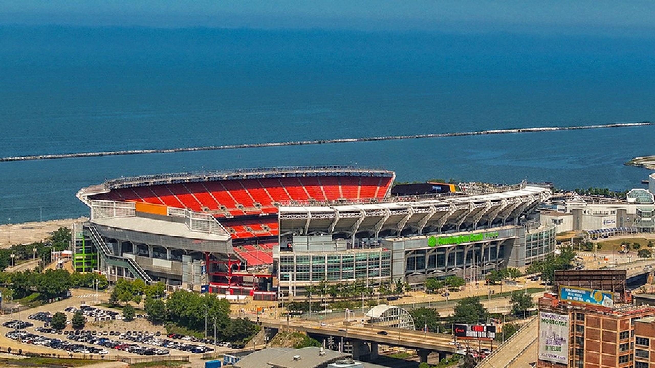 Spectacular aerial view of a vast stadium overlooking the serene blue waters, perfect for thrilling sports events and breathtaking lakeside vibes.