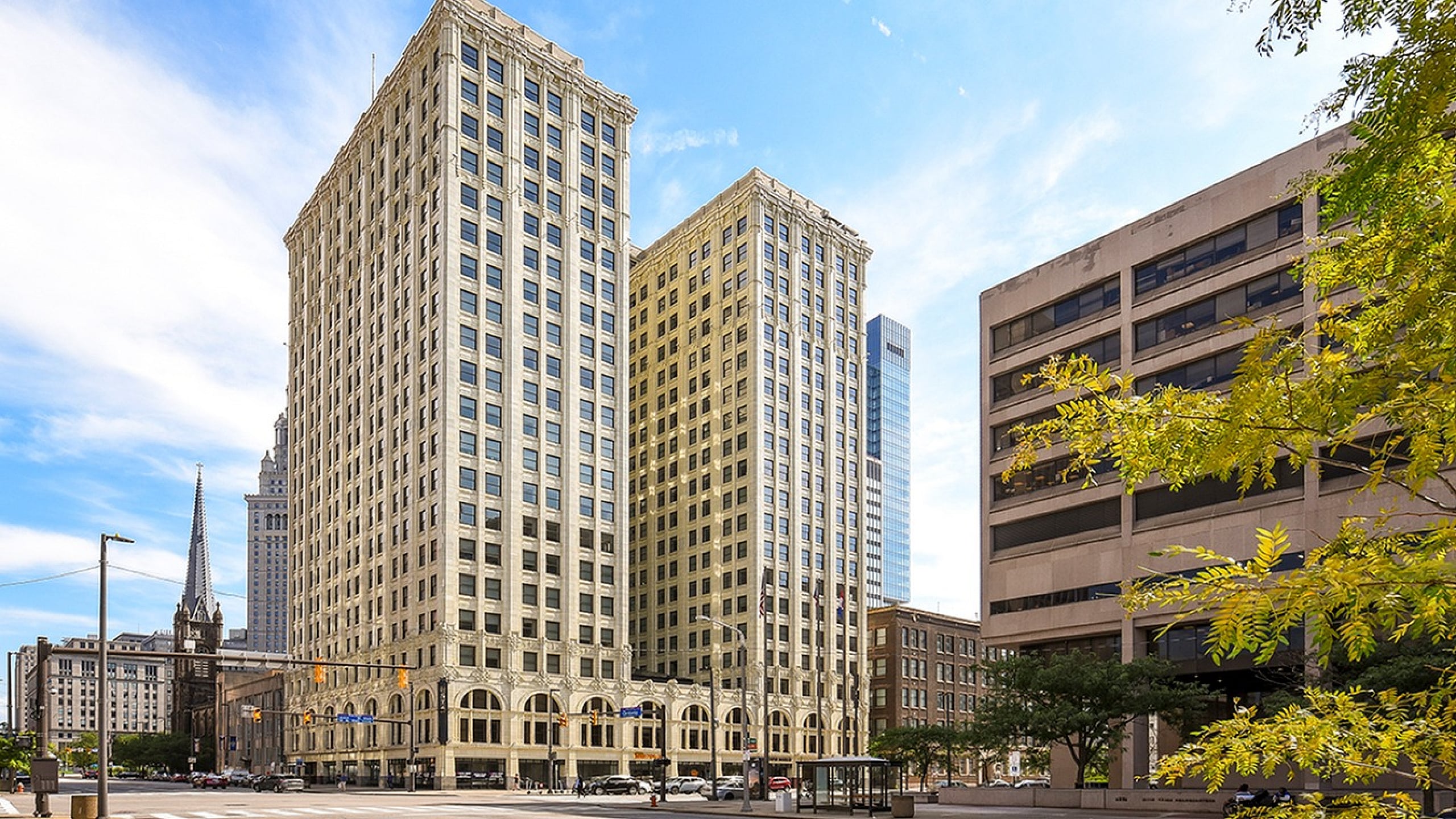 Impressive urban skyline featuring a historic, elegant high-rise building with classic architecture, set against a bright blue sky.