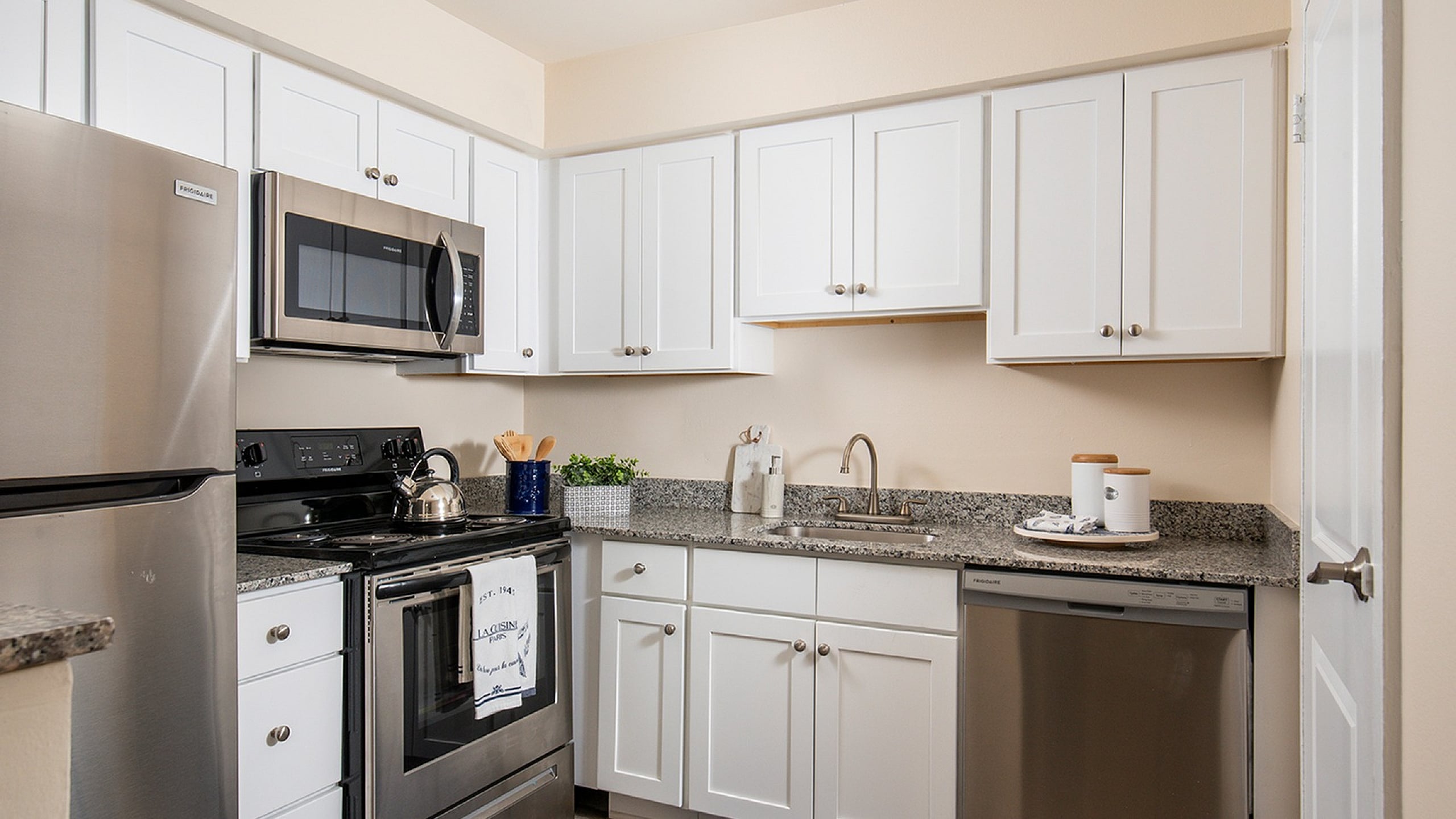 Modern kitchen with sleek stainless steel appliances, granite countertops, and elegant white cabinetry offering a bright and functional cooking space.