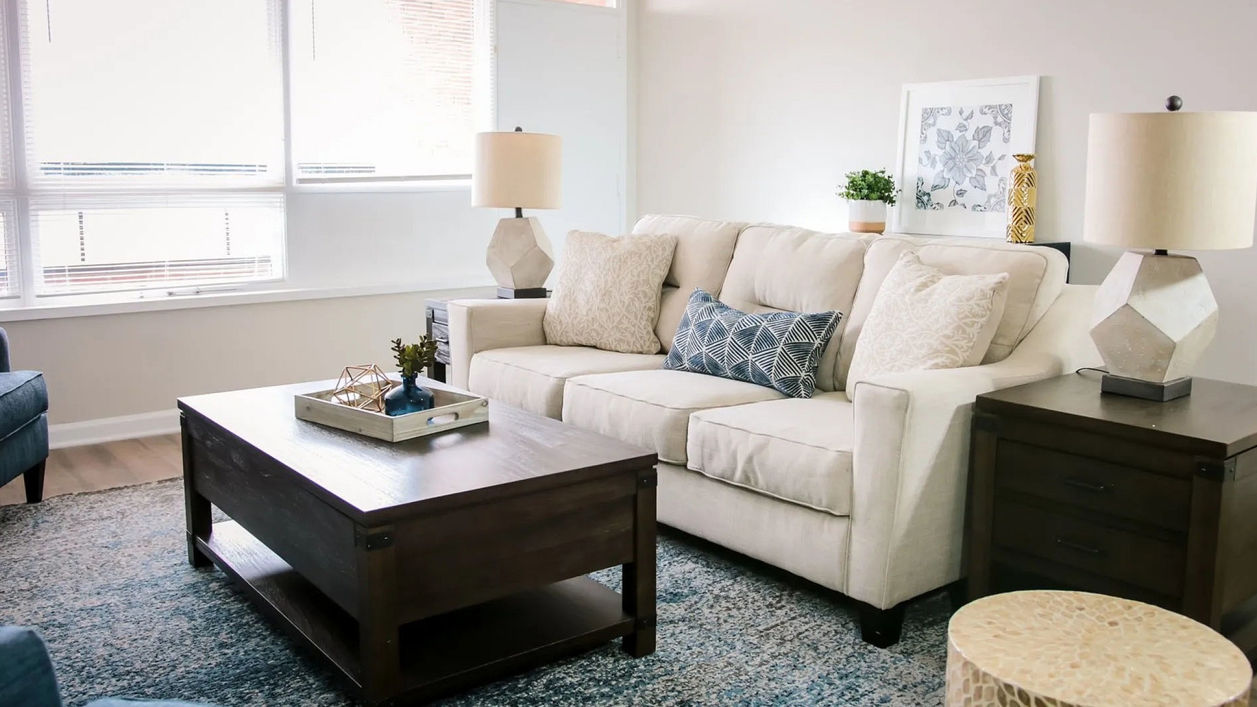 Bright and inviting living room featuring a plush beige sofa, modern geometric lamps, and a chic coffee table, complemented by a soothing blue and white color palette.