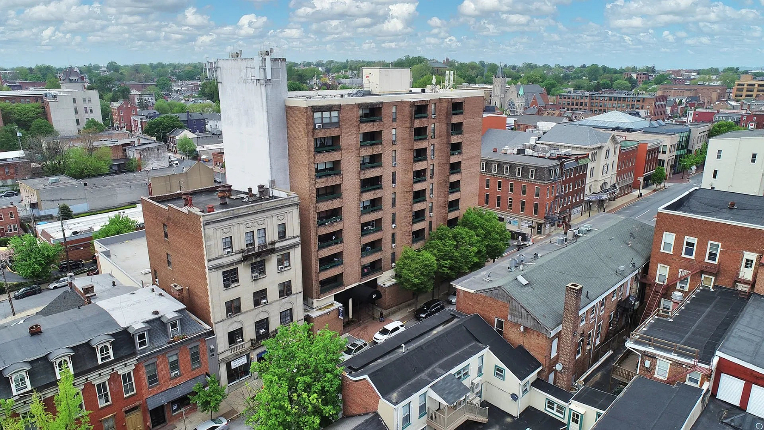 Charming urban residential building nestled in a vibrant cityscape, surrounded by lush greenery and historic architecture.