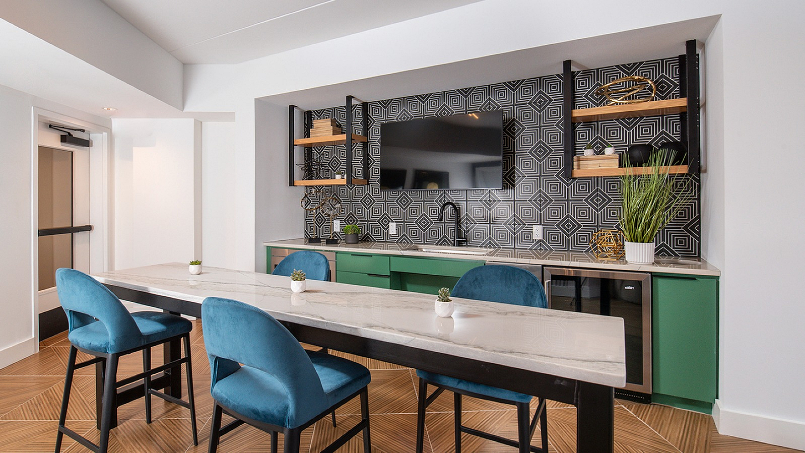 Modern kitchen space with geometric backsplash, sleek countertops, and bold blue chairs for stylish dining.