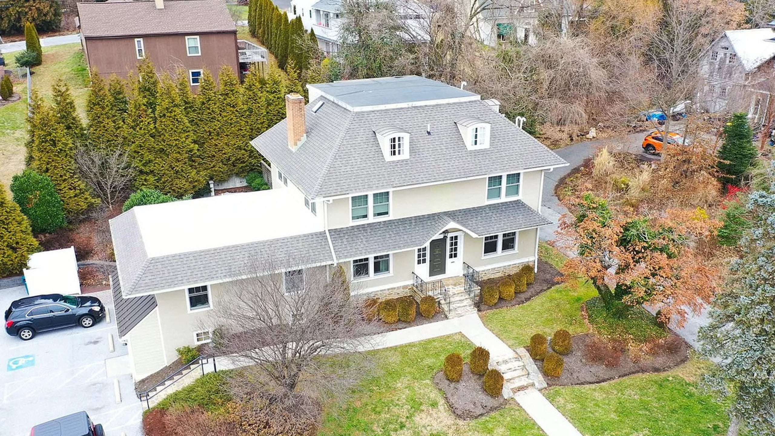 Charming aerial view of a spacious two-story house surrounded by lush greenery, featuring a manicured lawn and elegant landscaping.