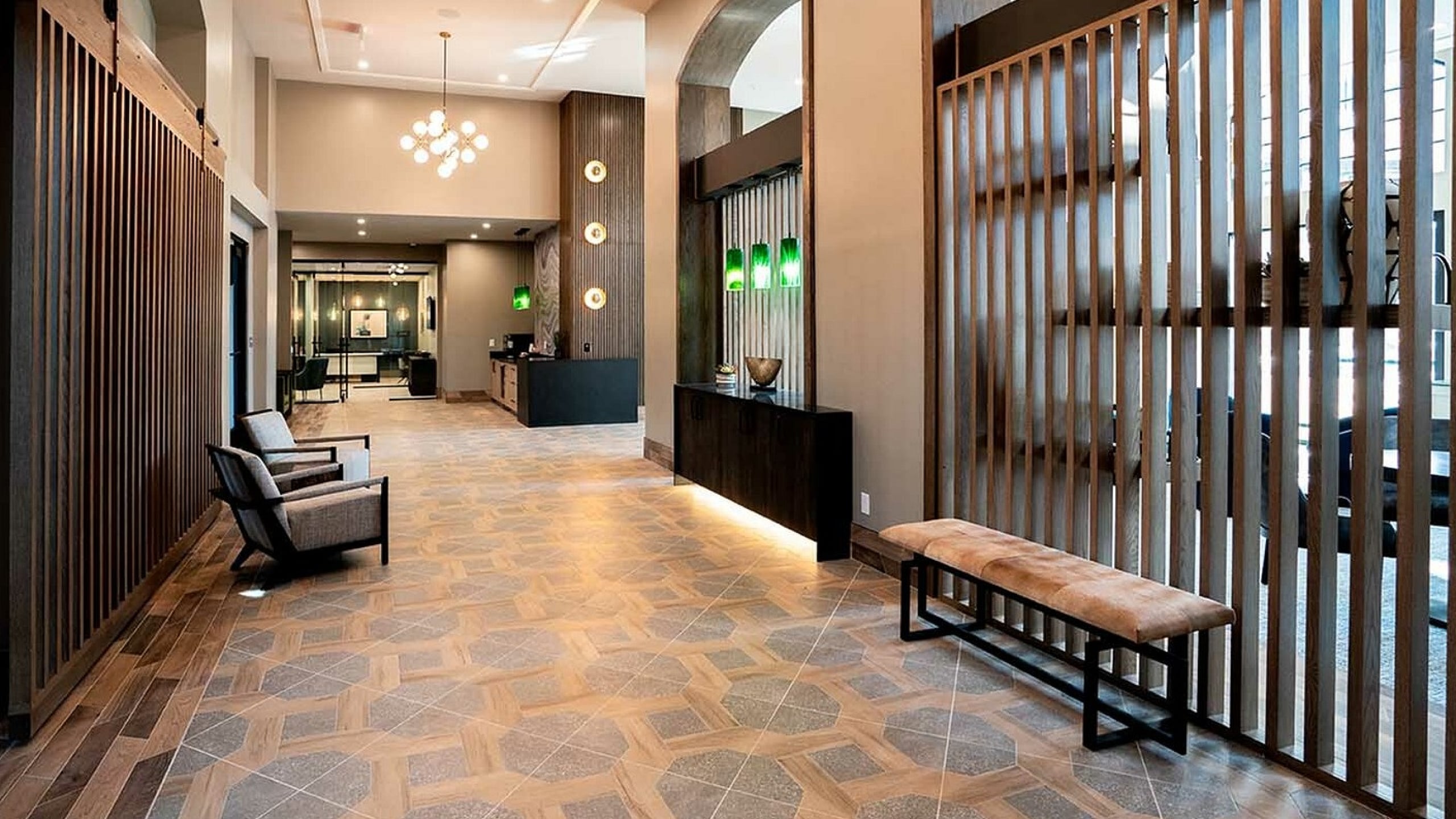 Elegant apartment lobby with geometric tile flooring, modern lighting, and stylish wood paneling, offering a welcoming ambiance.