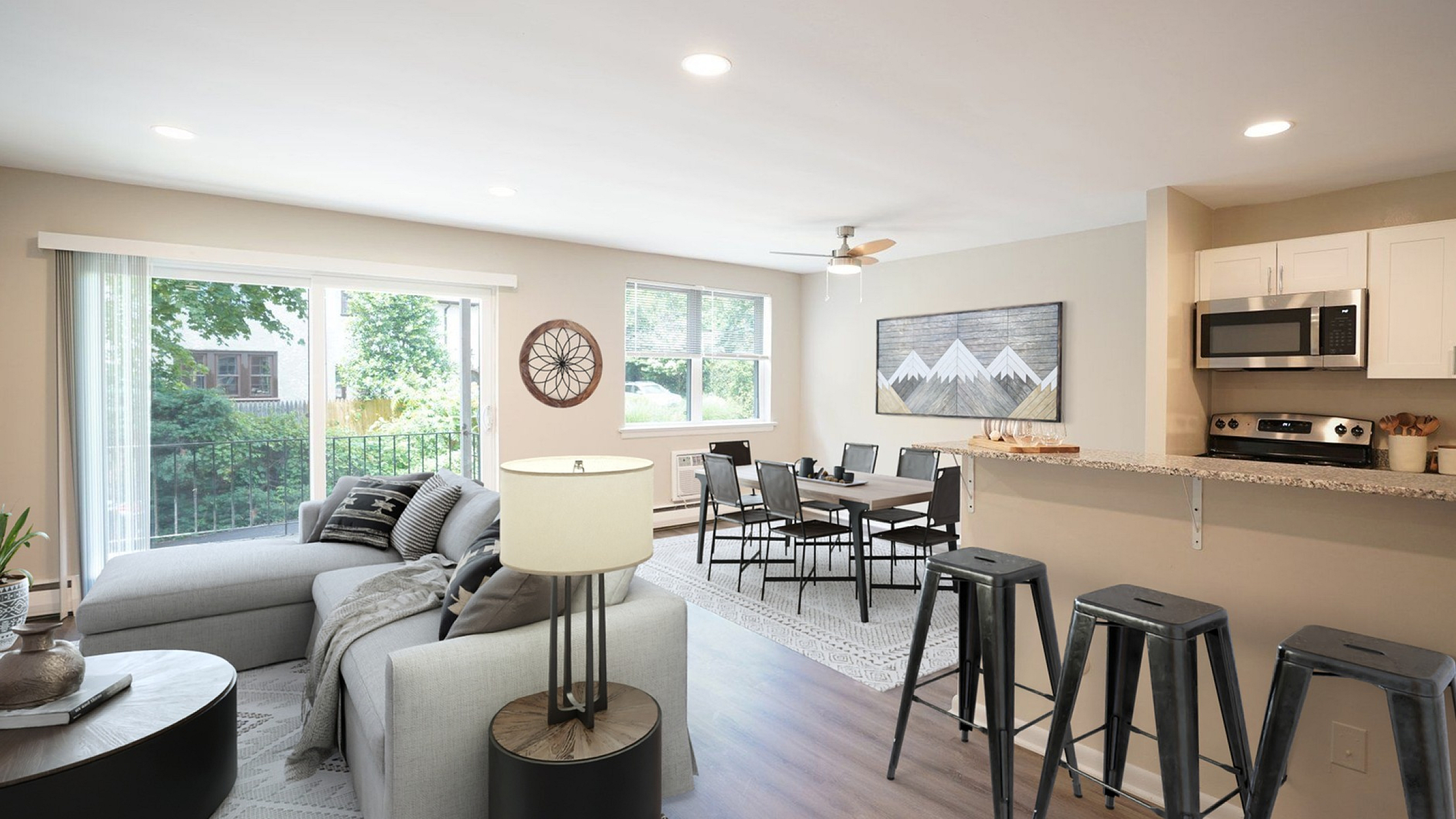 Contemporary open-concept living area with elegant decor, large windows, and a modern kitchen featuring a granite countertop and stainless steel appliances.