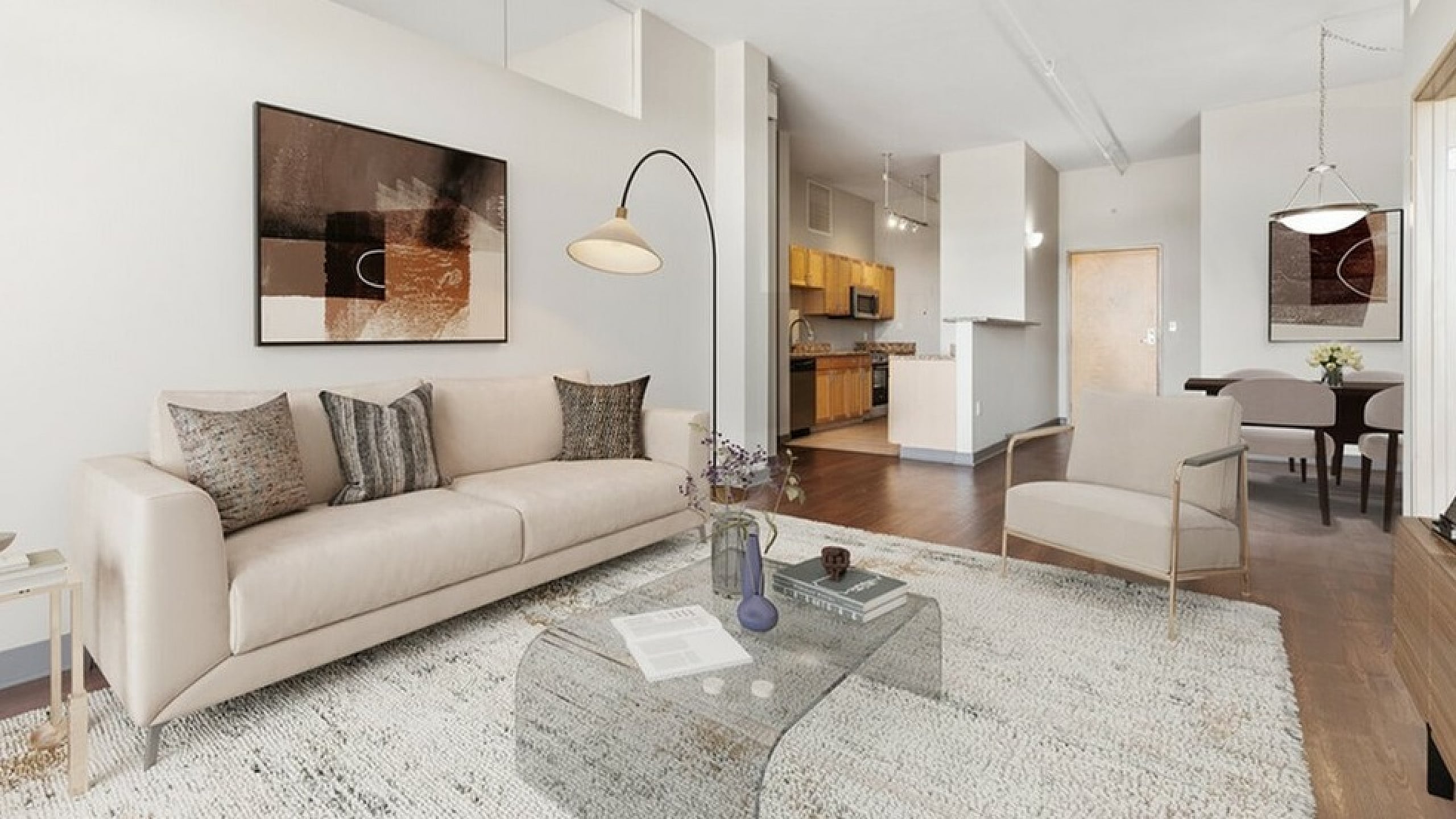 Modern open-plan living room with elegant decor, featuring a cozy sofa, stylish armchair, and a sleek glass table, seamlessly flowing into a spacious kitchen and dining area.