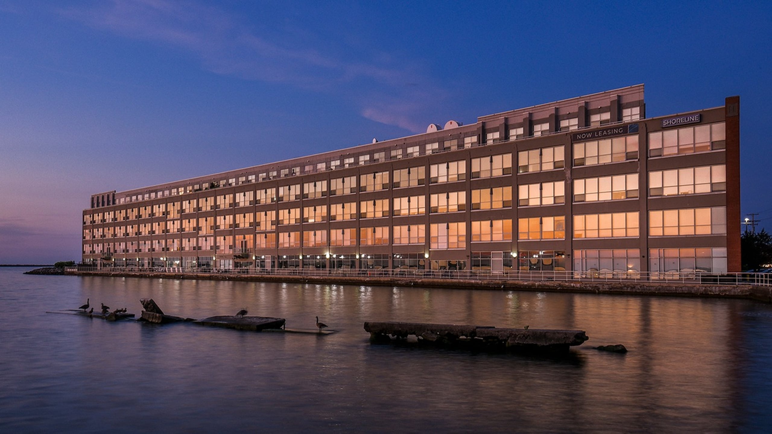 Elegant waterfront apartment building at dusk with a serene lakeside view.