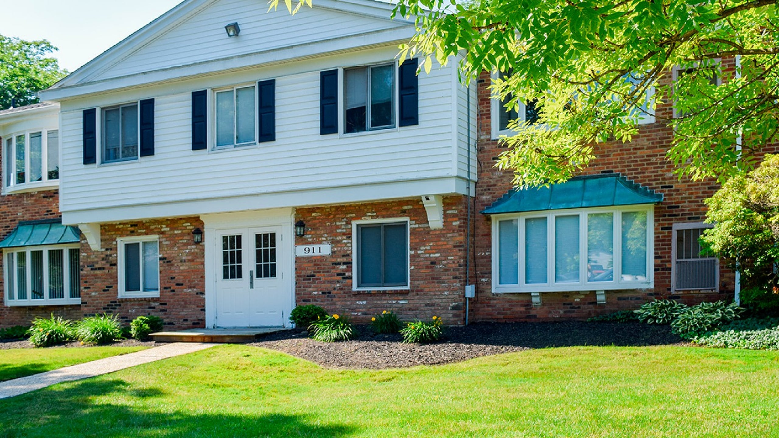 Charming brick apartment building with lush green lawn and inviting entrance.