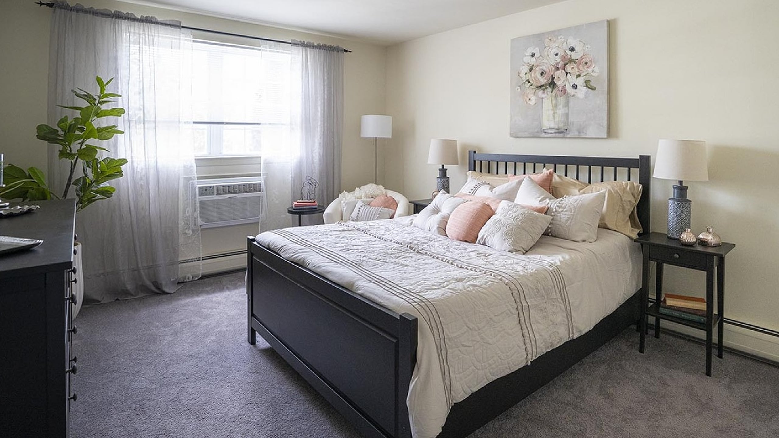 Inviting bedroom with elegant decor, featuring a plush bed, soft lighting, and a bright window with sheer curtains.