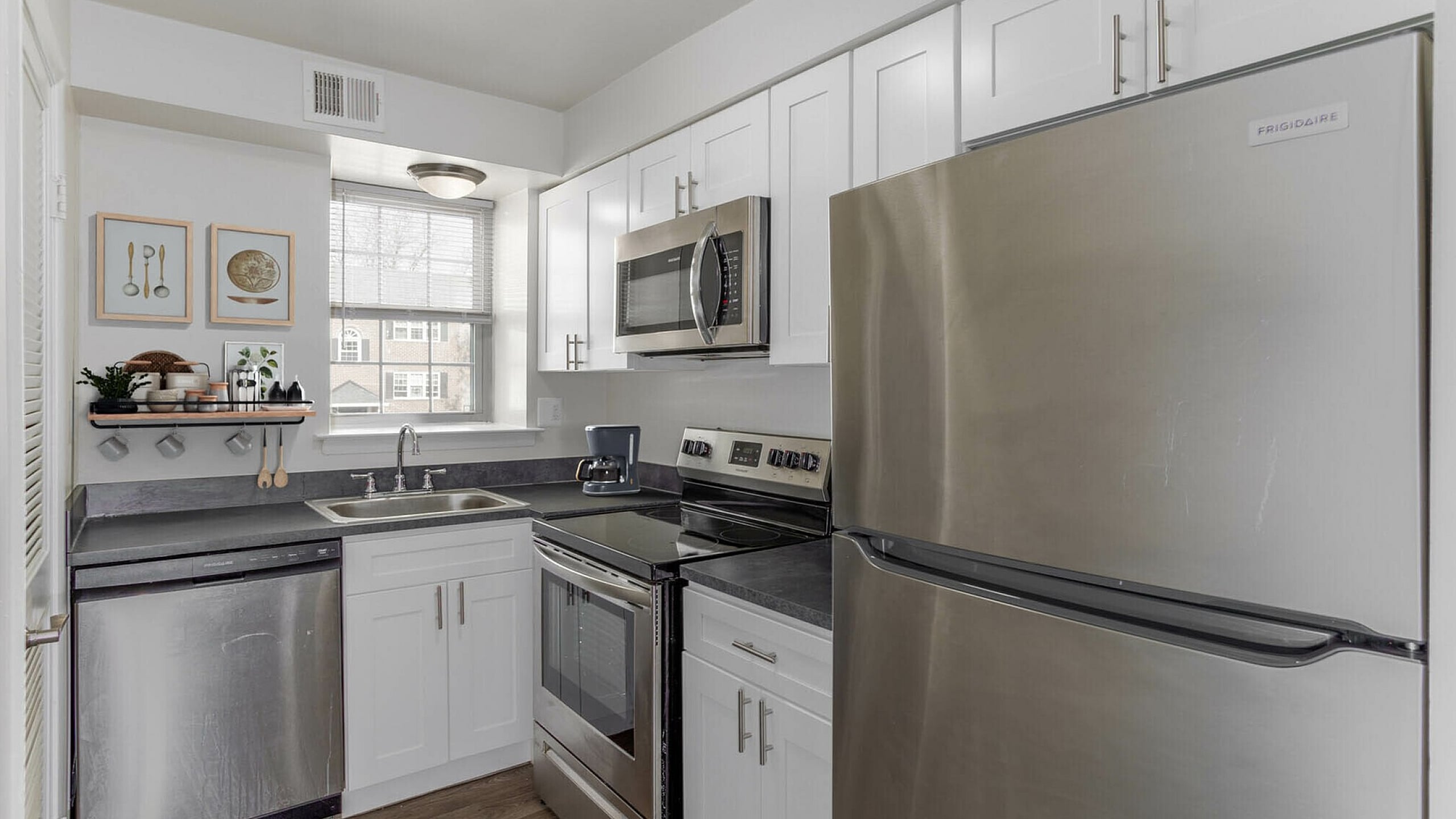 Modern kitchen with stainless steel appliances, sleek white cabinets, and elegant wood flooring.