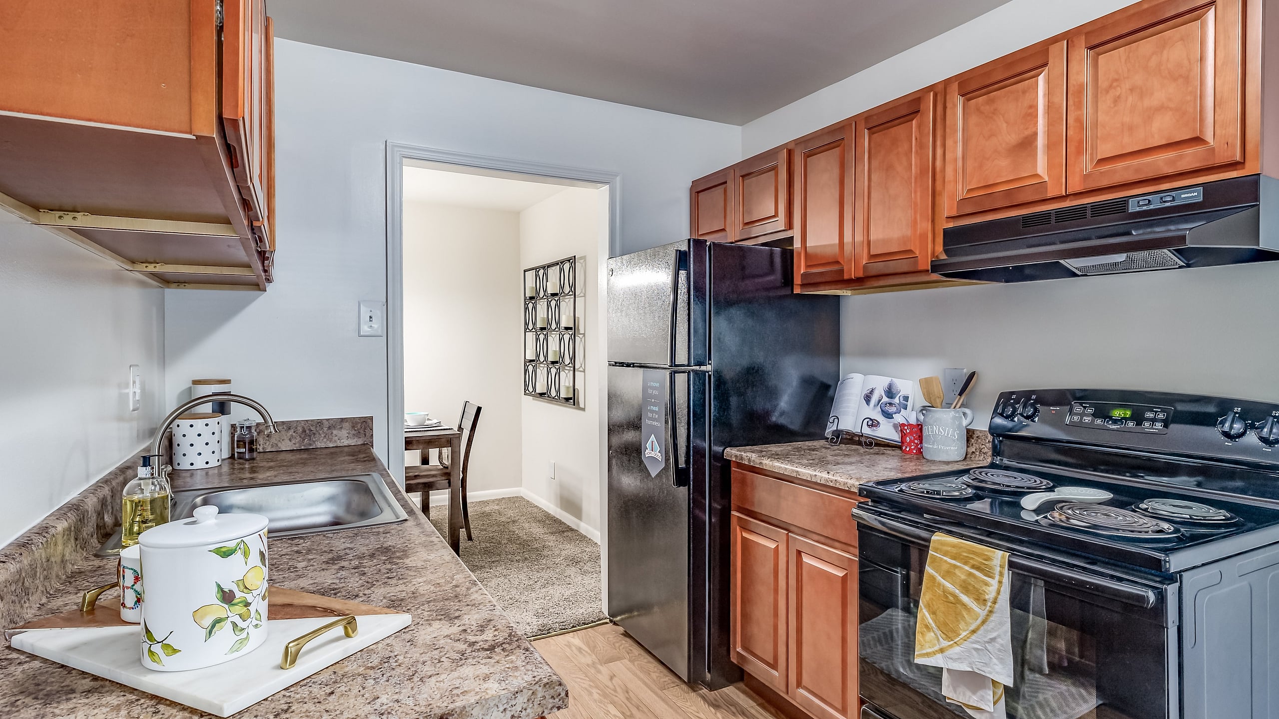 Modern kitchen with stylish wooden cabinets and sleek countertops, featuring a black refrigerator and stove, offering a cozy and functional cooking space.