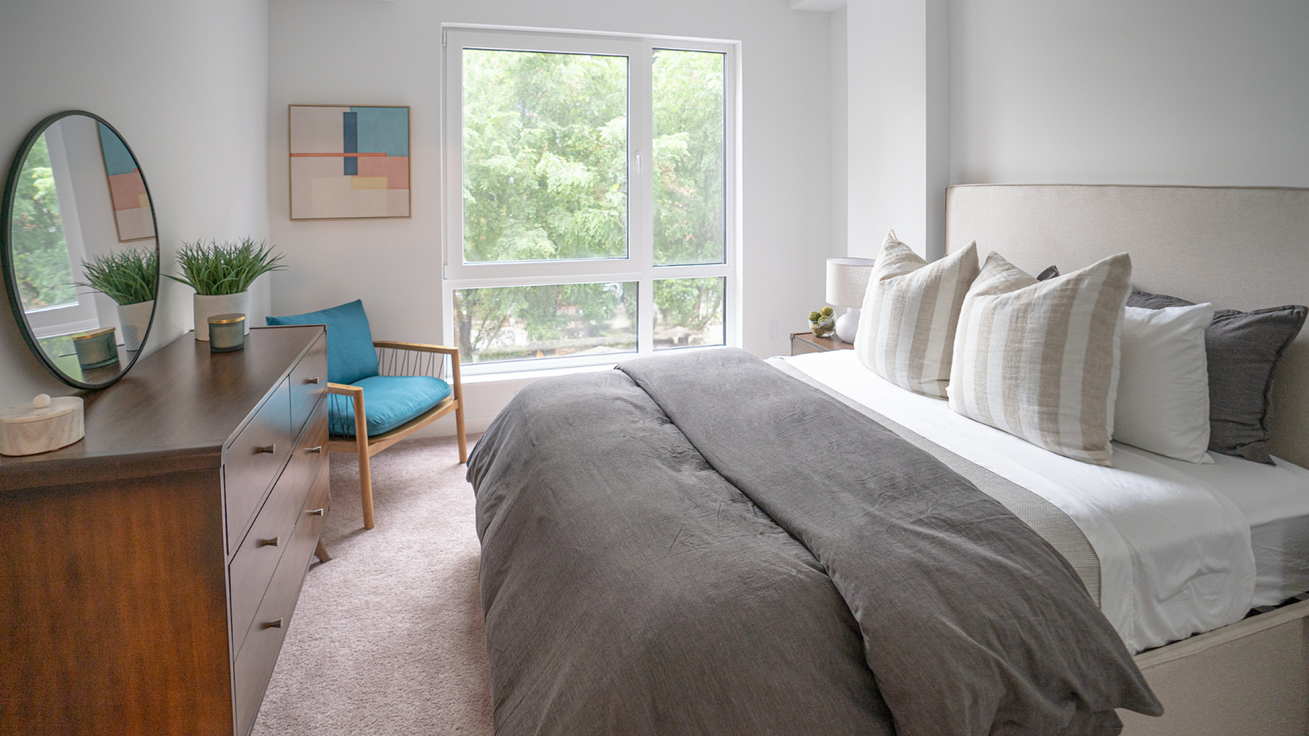 Bright, modern bedroom with large windows, stylish decor, and a cozy reading nook.