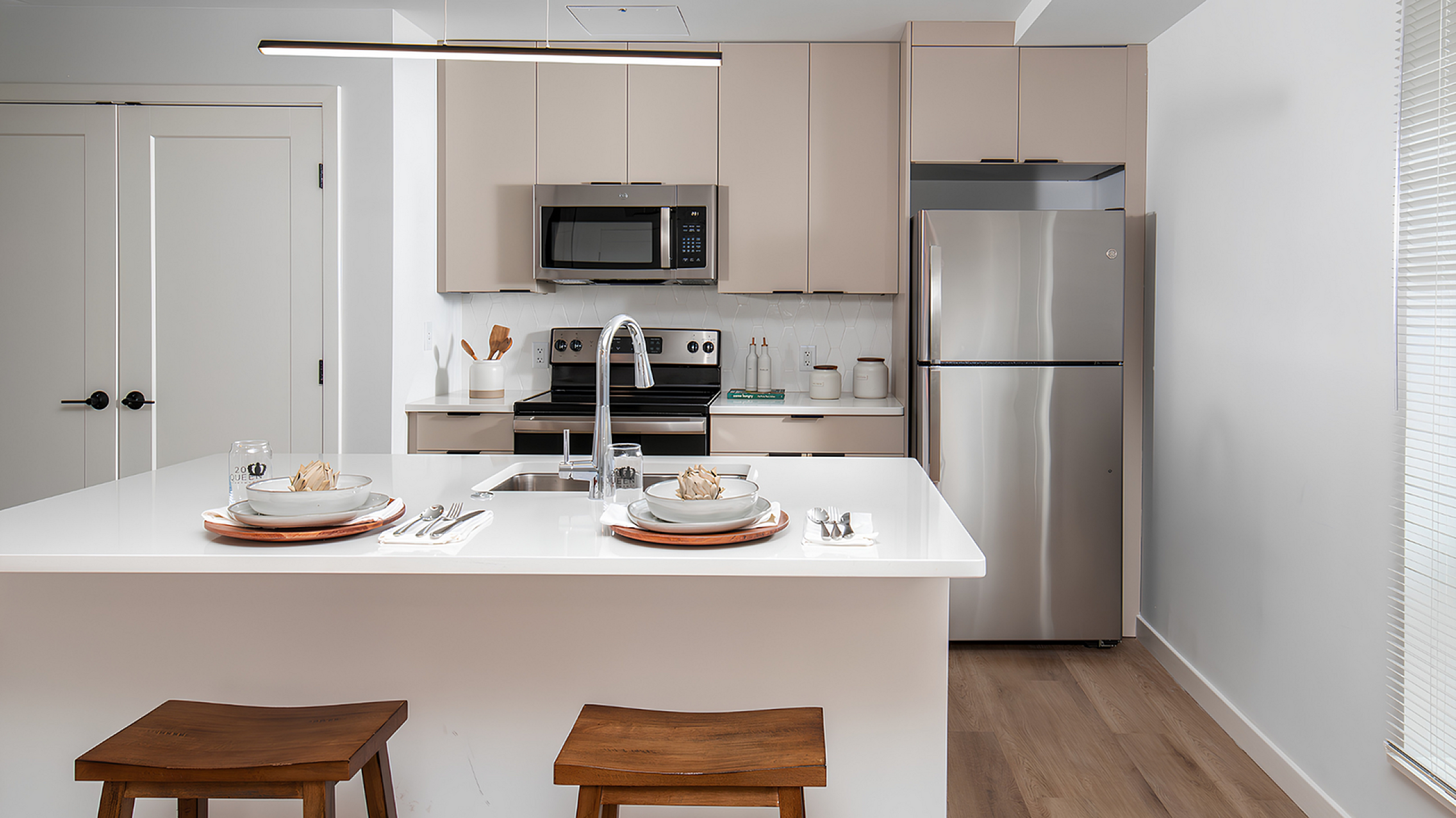 Modern kitchen with sleek stainless steel appliances, elegant cabinetry, and a chic white island with cozy wooden stools.