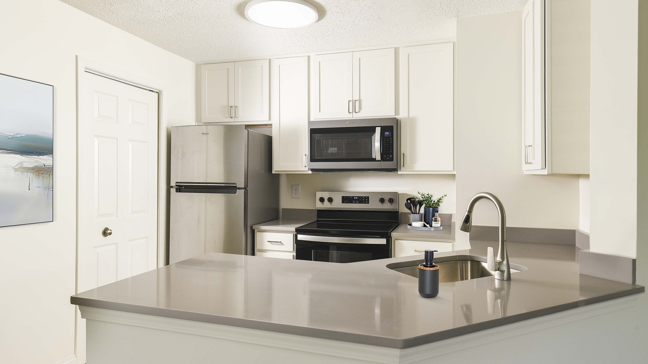 Modern kitchen with sleek appliances, a stainless steel refrigerator, and minimalist countertops, exuding a sophisticated ambiance.