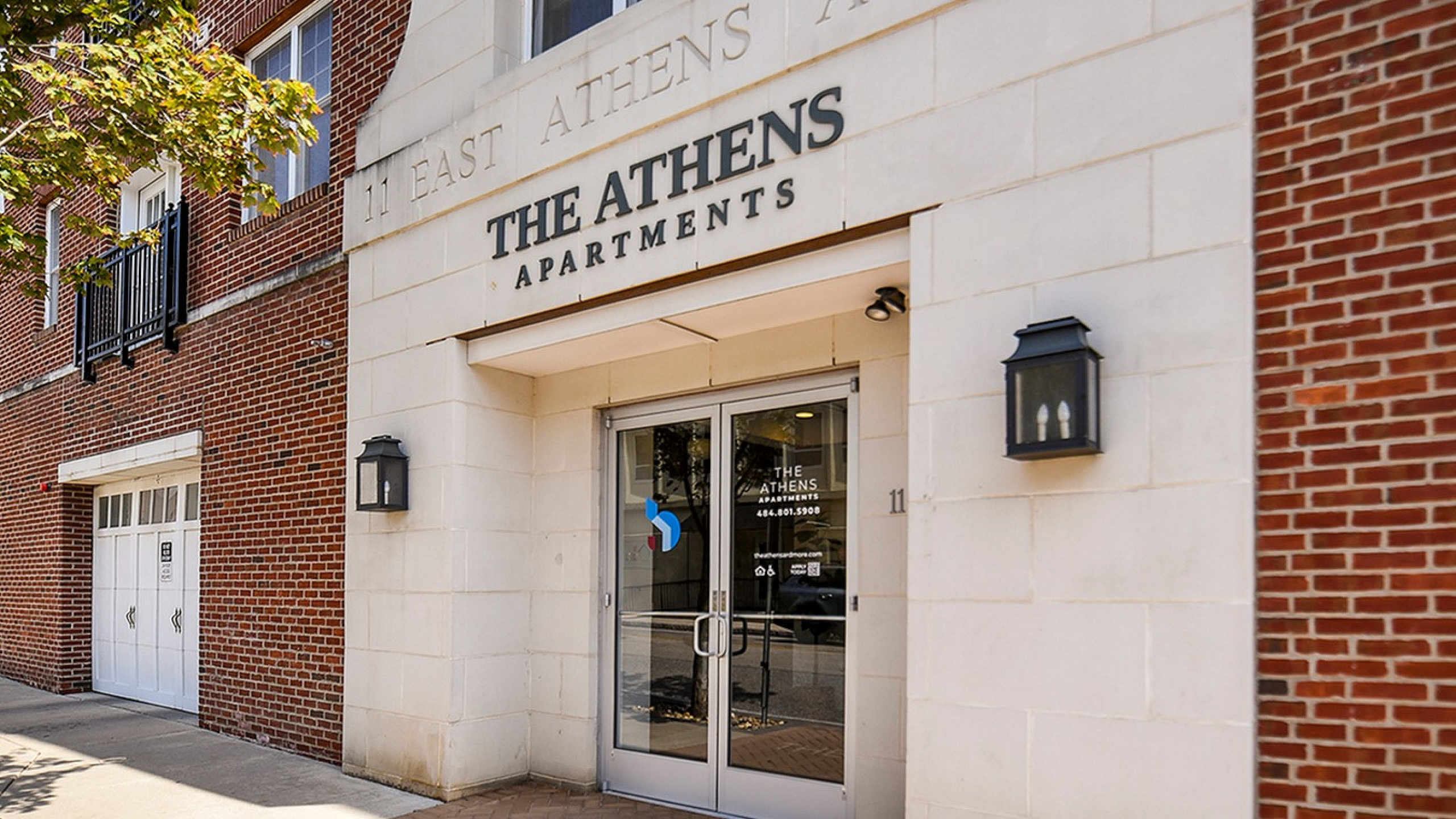 Inviting entrance of The Athens Apartments with elegant brick facade and modern glass doors.
