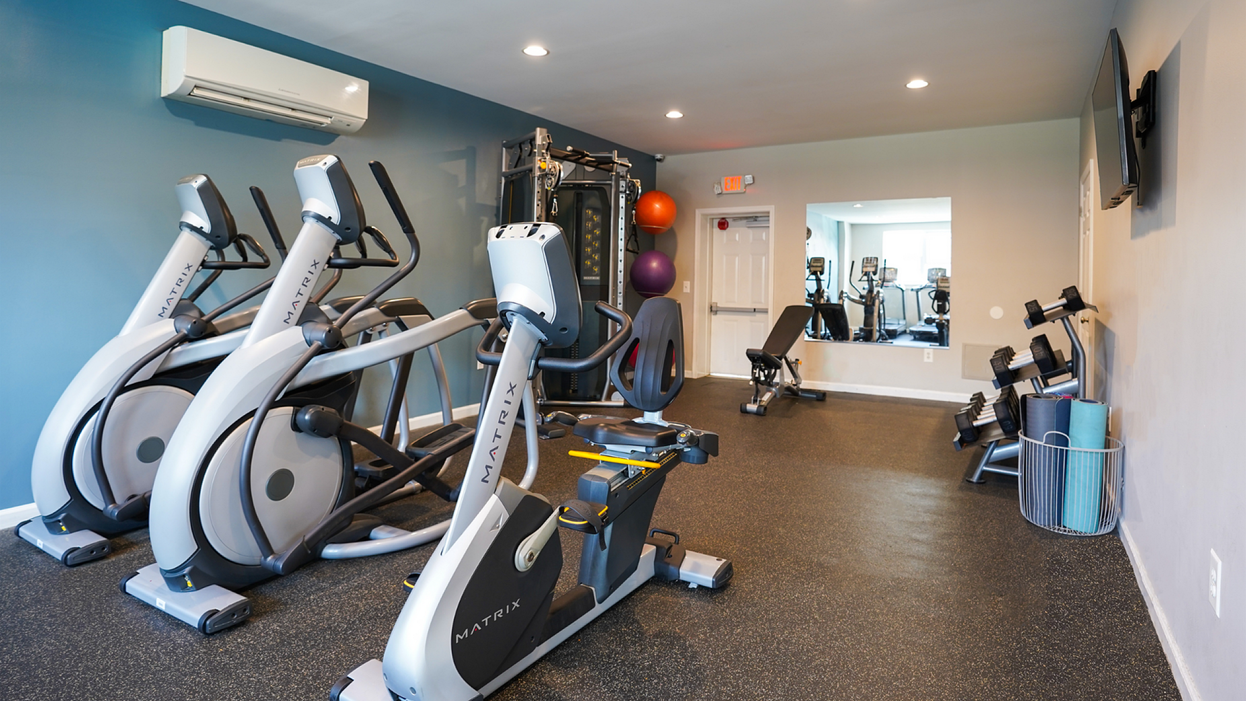 Modern fitness center equipped with state-of-the-art exercise machines, weights, and yoga mats in a sleek, spacious room.