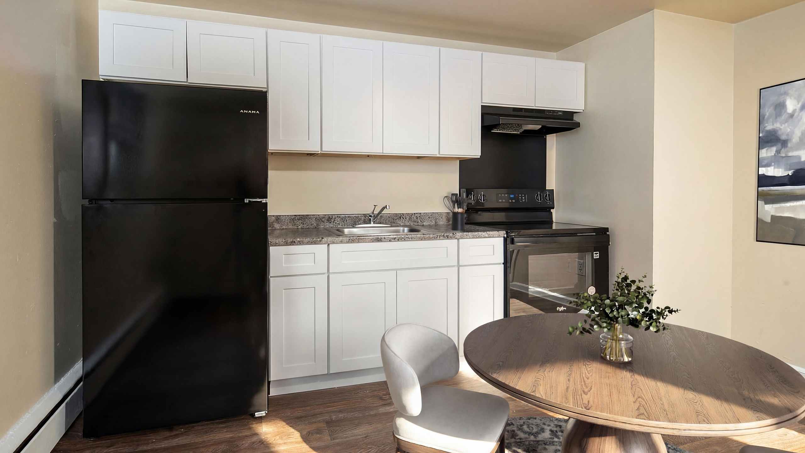 Modern kitchen with sleek black appliances and elegant dining area featuring a chic wooden table and chairs.