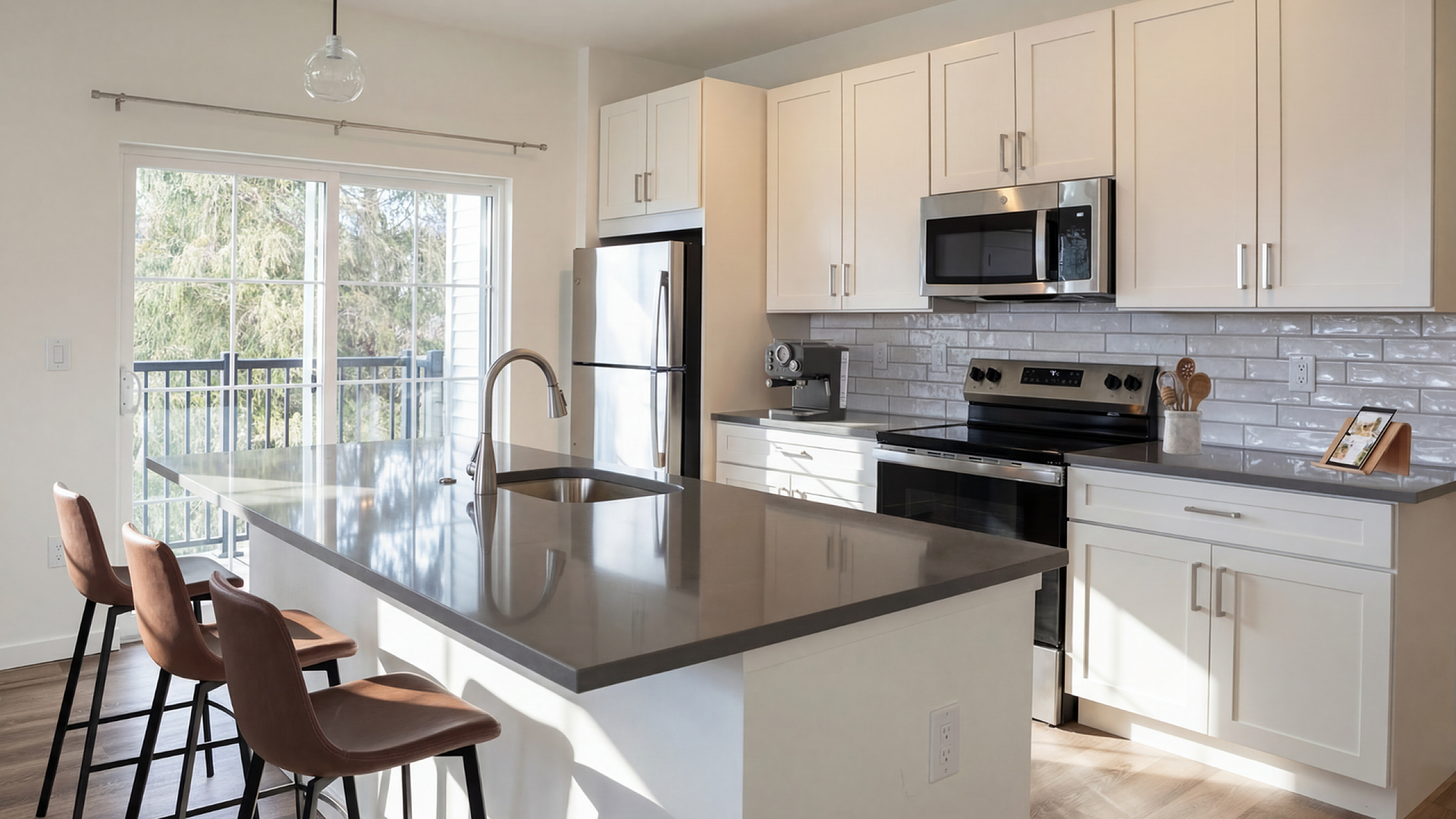 Modern kitchen with sleek countertops, stainless steel appliances, and stylish bar seating overlooking a sunny balcony view.