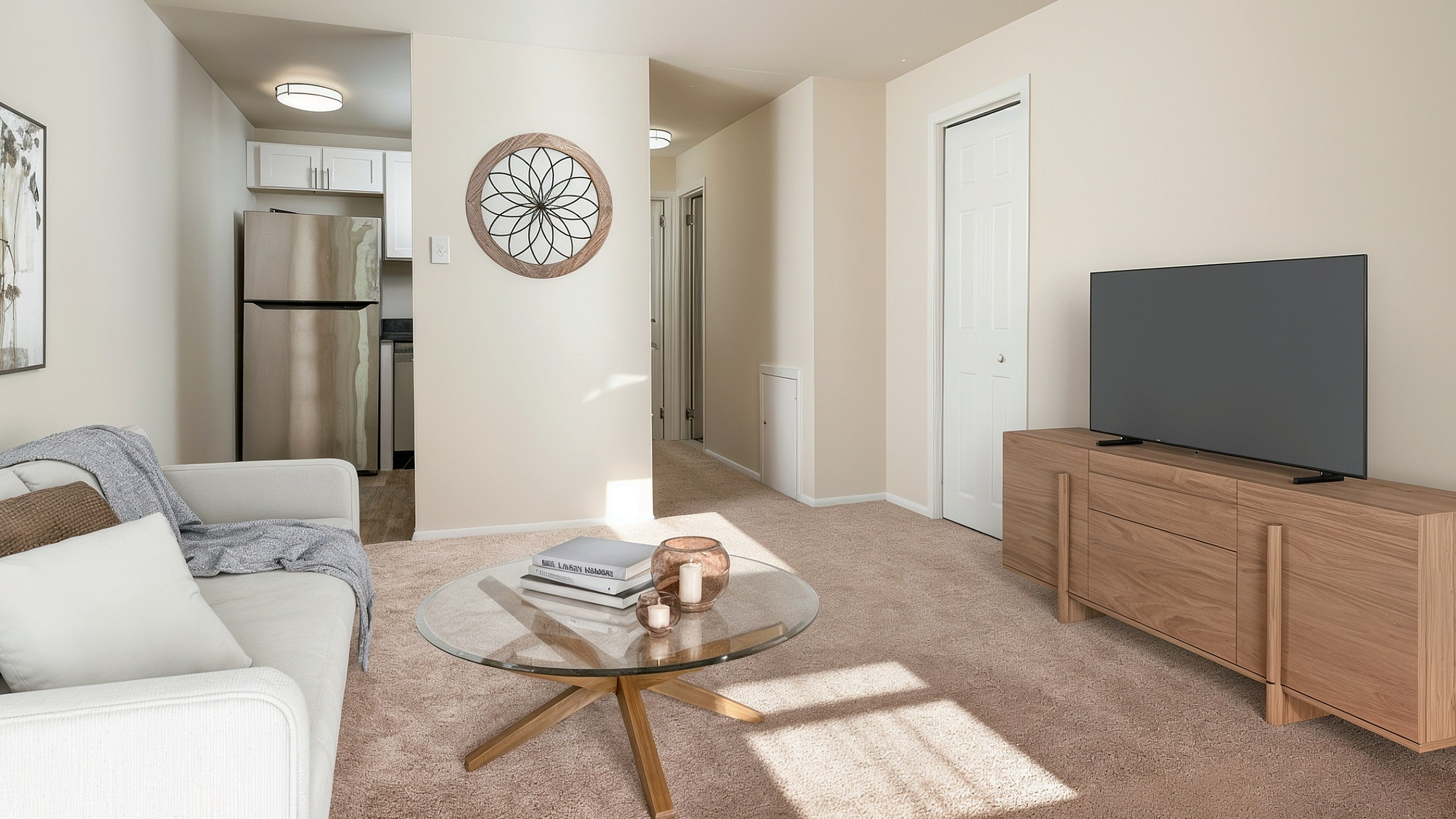 Chic apartment living area featuring modern decor, cozy beige carpeting, and a sleek kitchen with stainless steel appliances.