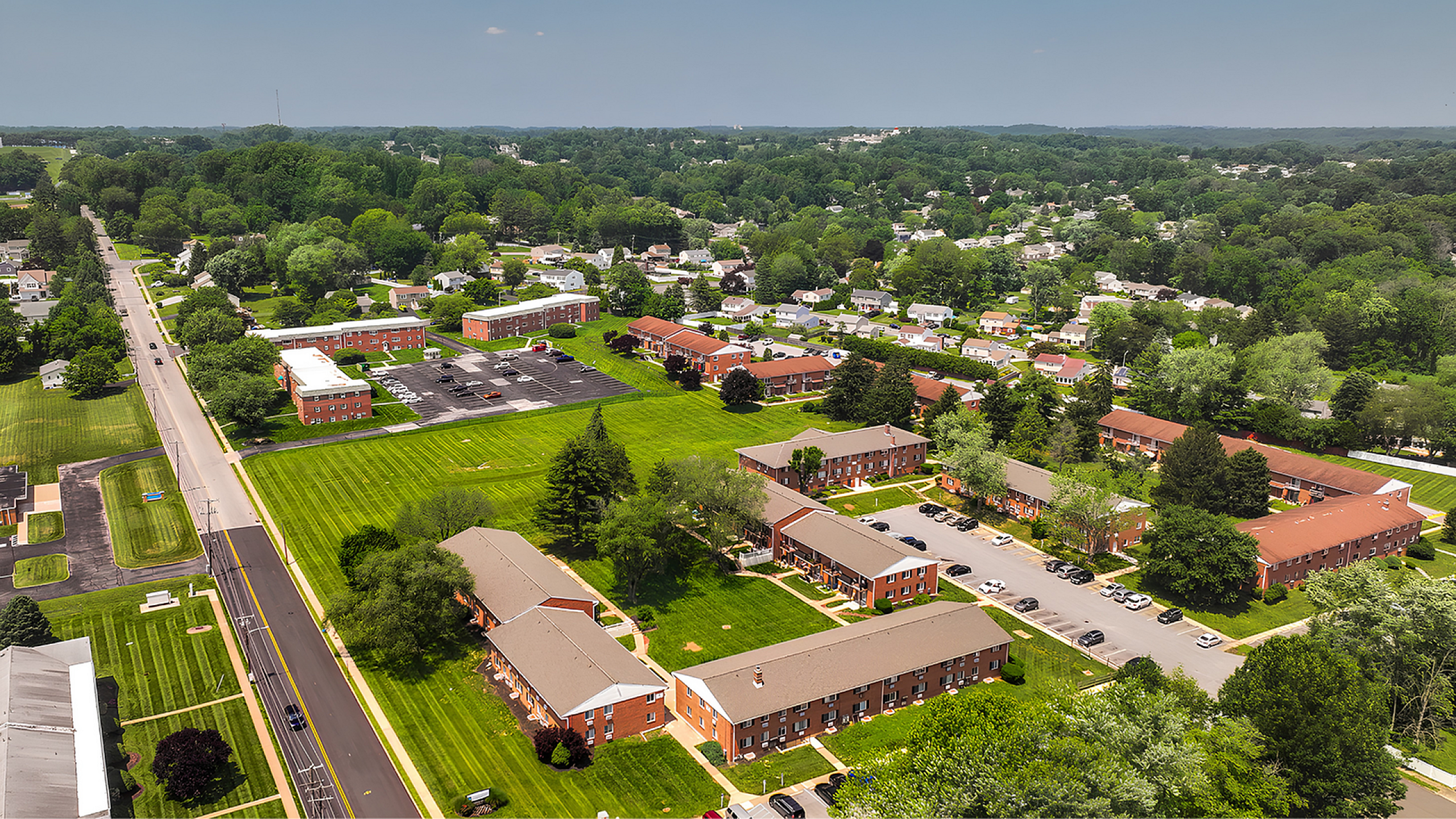 Scenic aerial view of a charming apartment complex surrounded by lush greenery and peaceful suburban streets, showcasing vibrant community living.