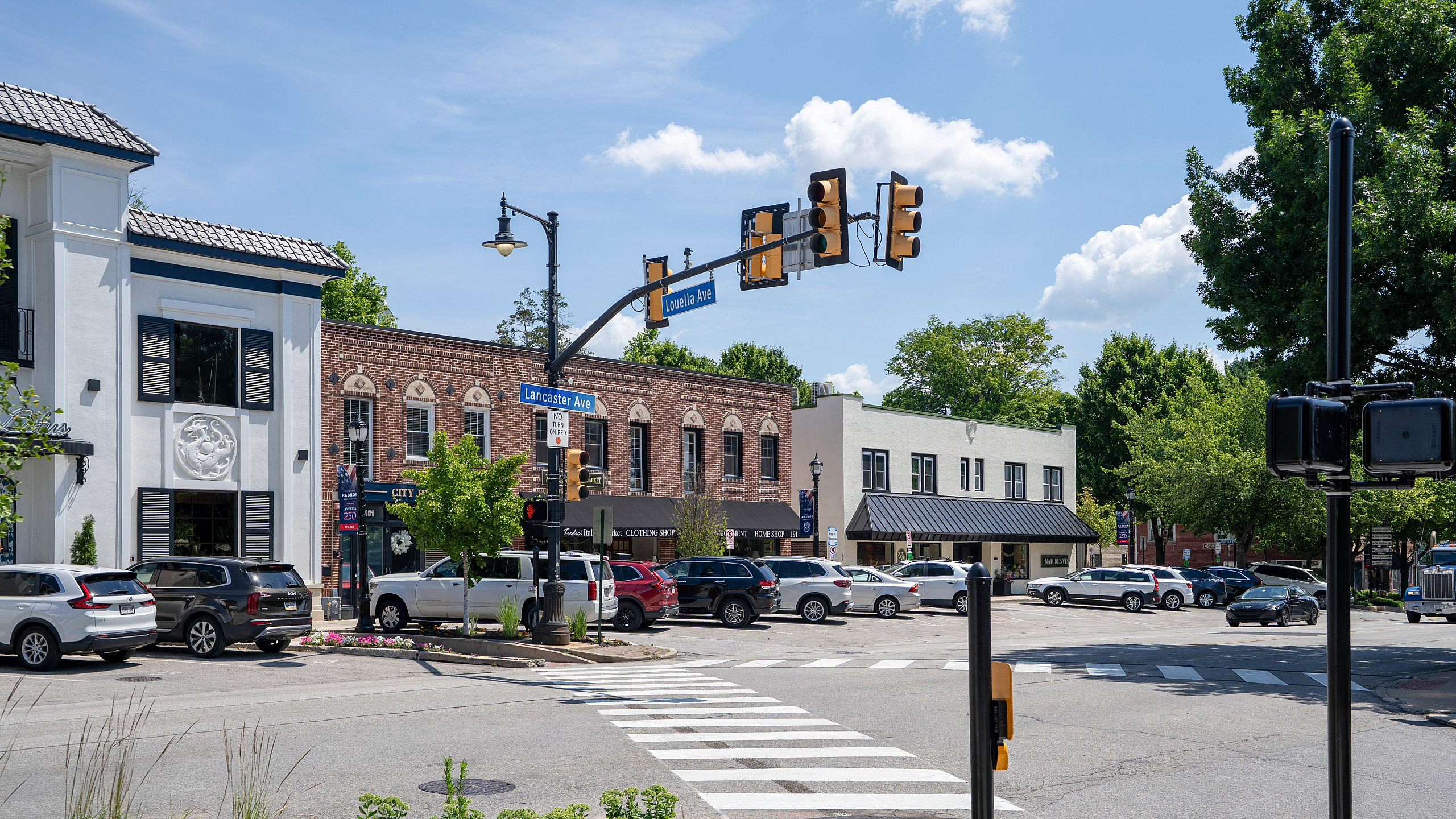 Charming downtown intersection with quaint shops and vibrant greenery under a clear blue sky.