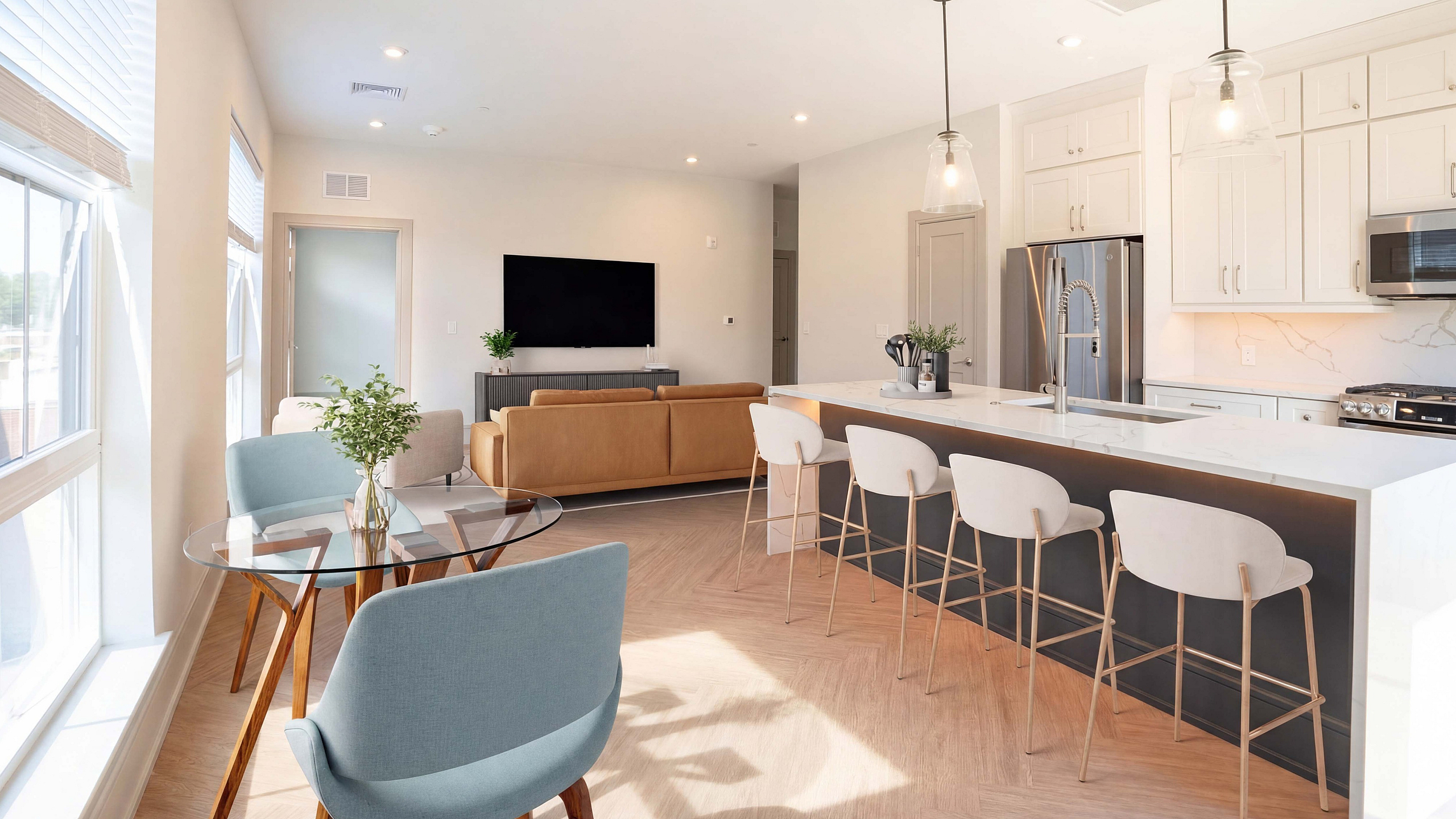 Bright and modern open-concept kitchen and living area with sleek countertops, stylish bar seating, and abundant natural light.