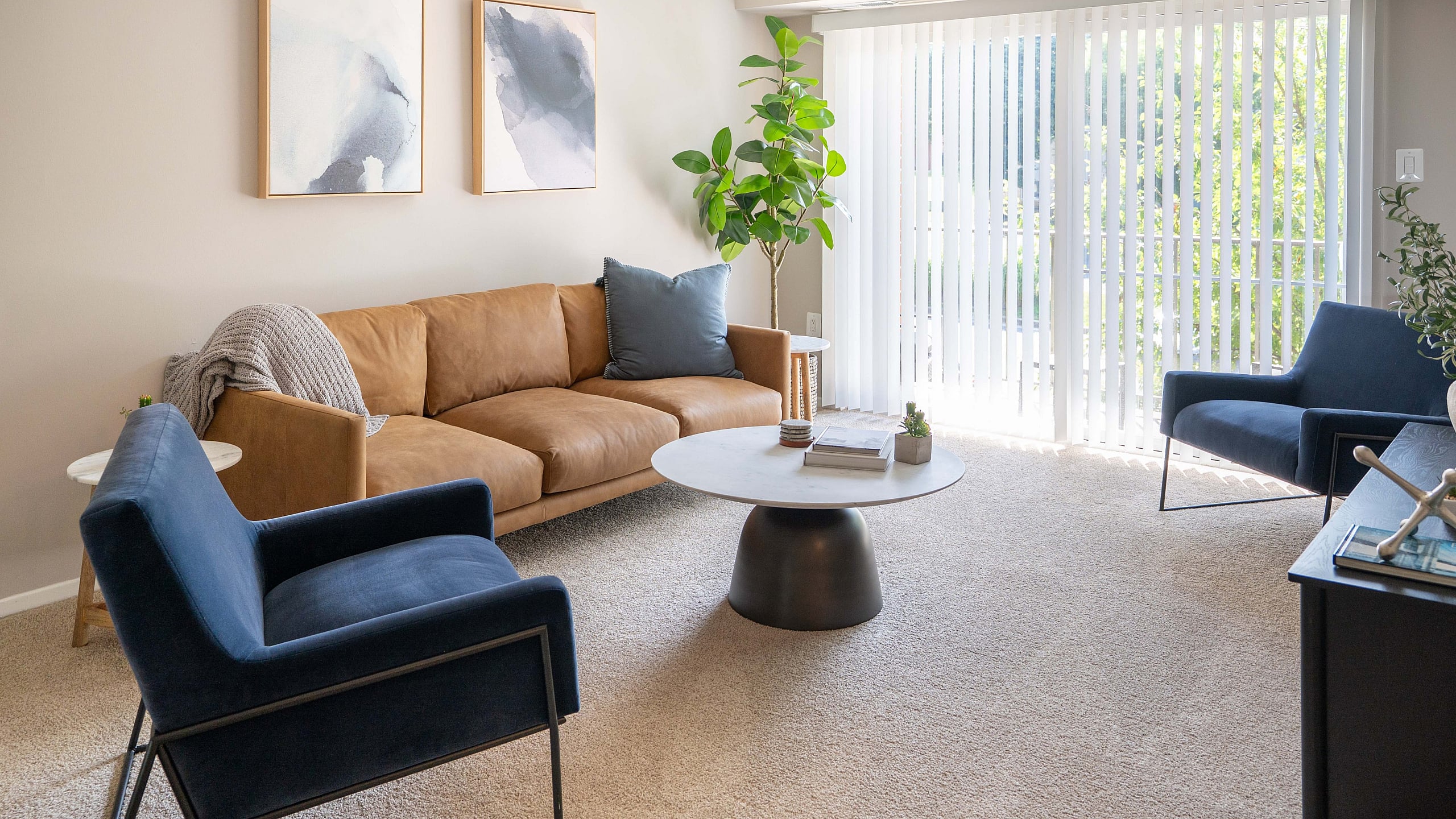 Bright, modern living room with a cozy tan sofa, chic blue chairs, and large windows offering natural light.