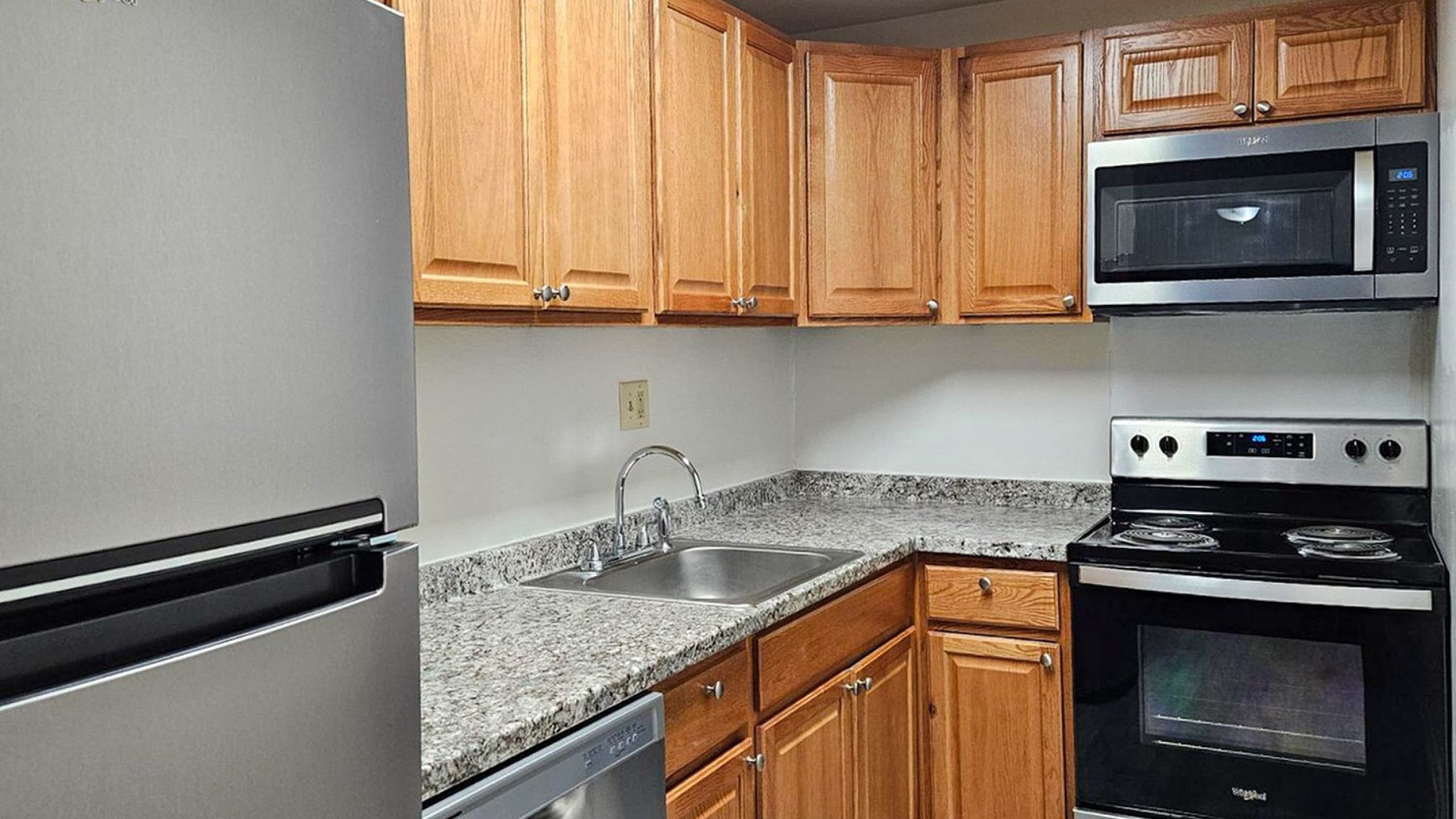 Modern kitchen with sleek stainless steel appliances, elegant granite countertops, and warm wooden cabinetry.