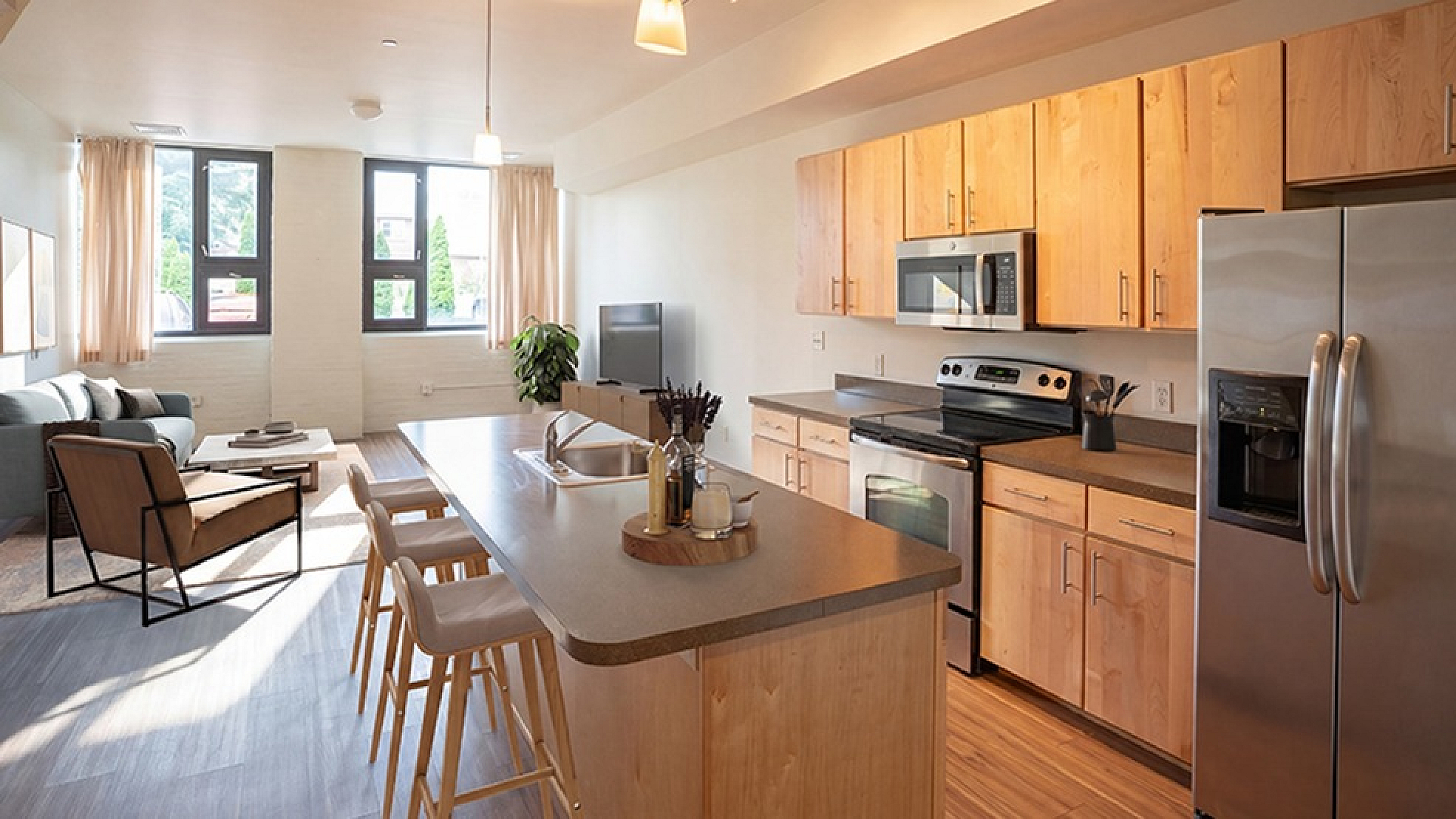 Bright, modern apartment with open-concept kitchen featuring stainless steel appliances, cozy living area with ample natural light, and stylish wood cabinetry.