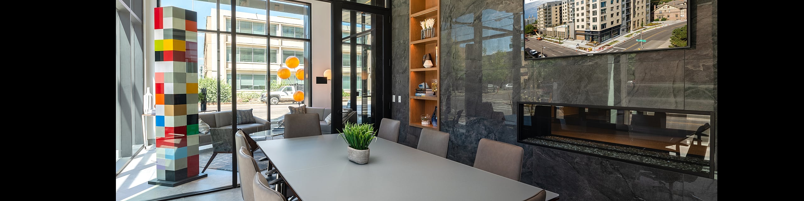 Modern conference room with sleek table, designer chairs, colorful art, and large windows for natural light.