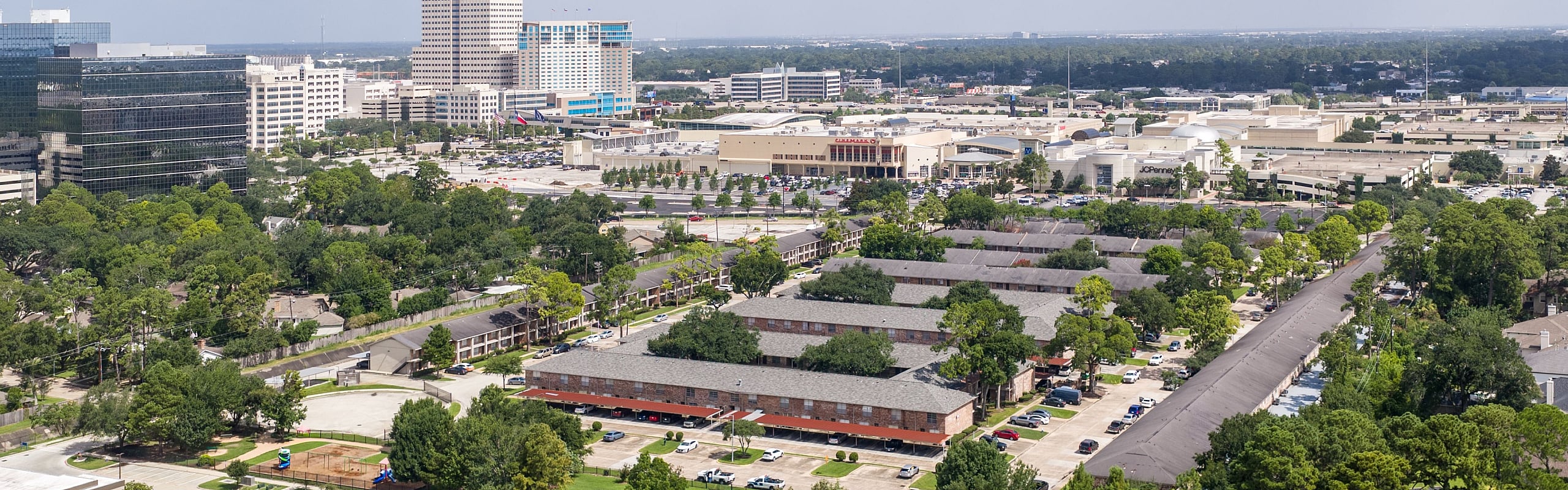 Vibrant aerial view of a bustling urban landscape featuring lush green areas, modern buildings, and a residential community surrounded by nature.