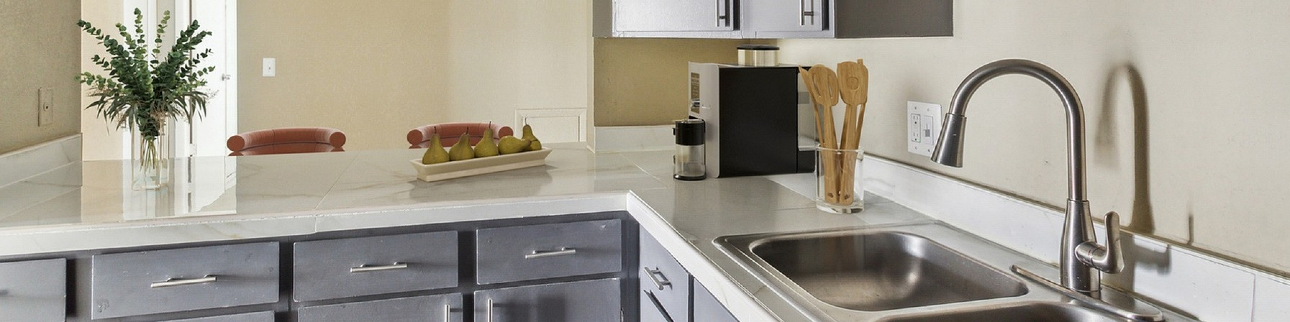 Modern kitchen with sleek gray cabinetry, dual sink, and elegant countertop featuring stylish decor and vibrant accents.