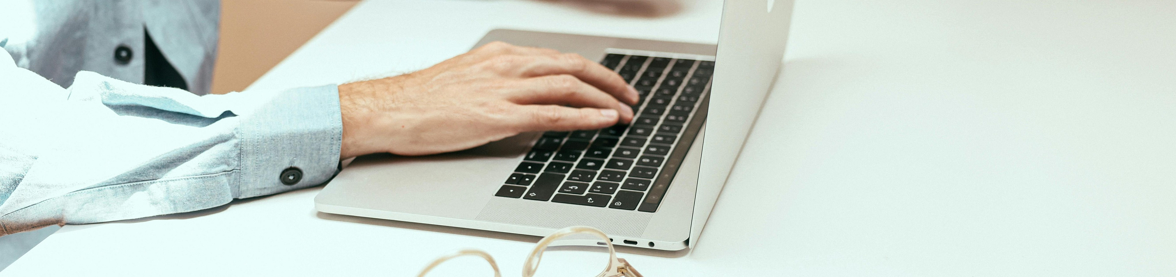 Person working at a sleek, modern desk with a laptop and coffee, emphasizing a minimalist and productive workspace.