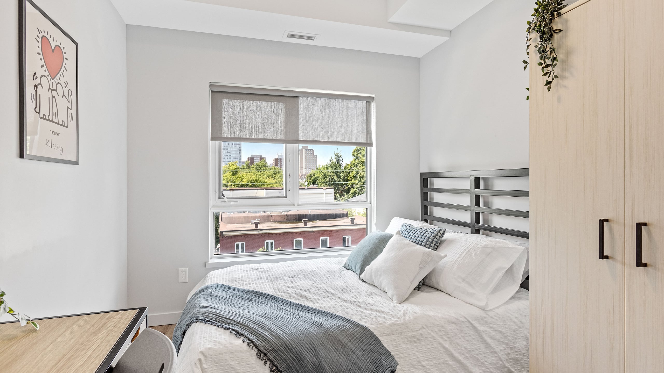 Bright, cozy bedroom with a comfortable bed, modern decor, and large window offering a city view.