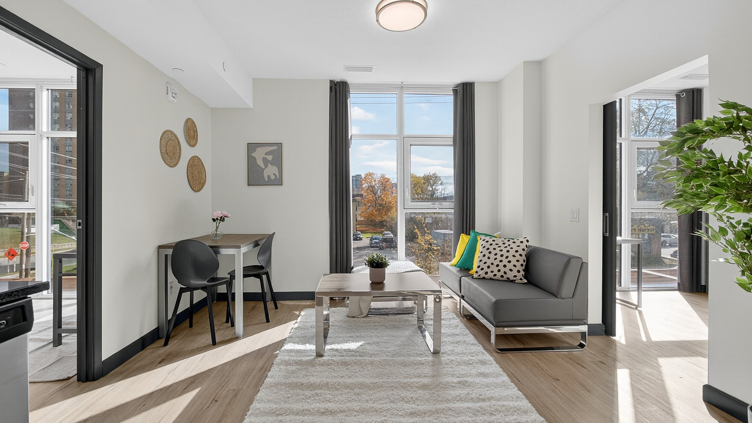 Bright modern living room with large windows, cozy seating area, stylish decor, and cheerful accents, perfect for comfort and relaxation.
